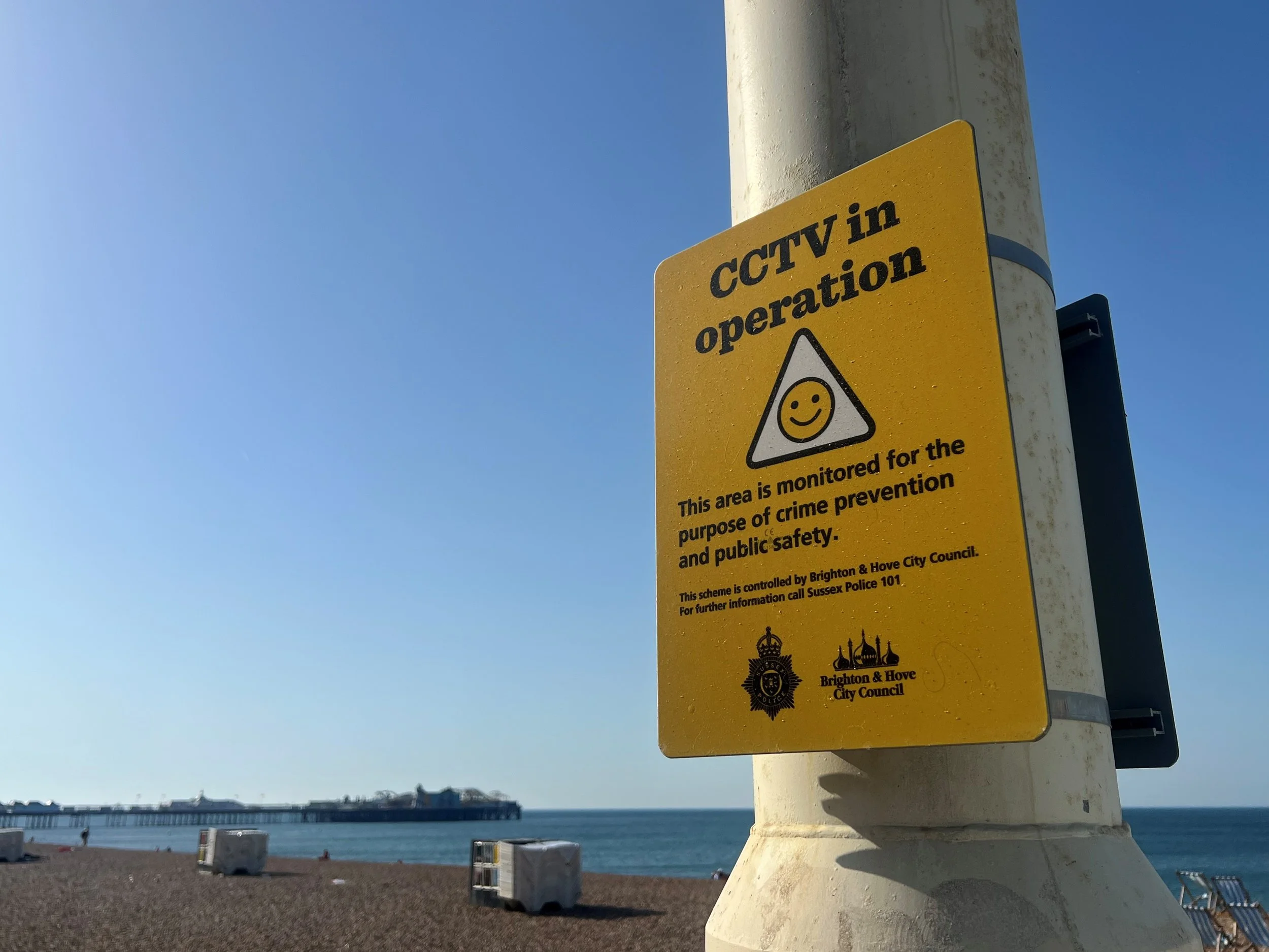 CCTV in operation sign on Brighton seafront with the pier and beach in the background
