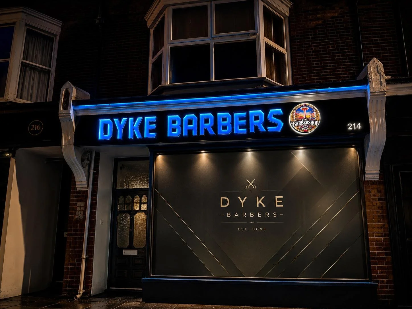 The Dyke Barbers shopfront lit up at night at 214 Dyke Road, Brighton