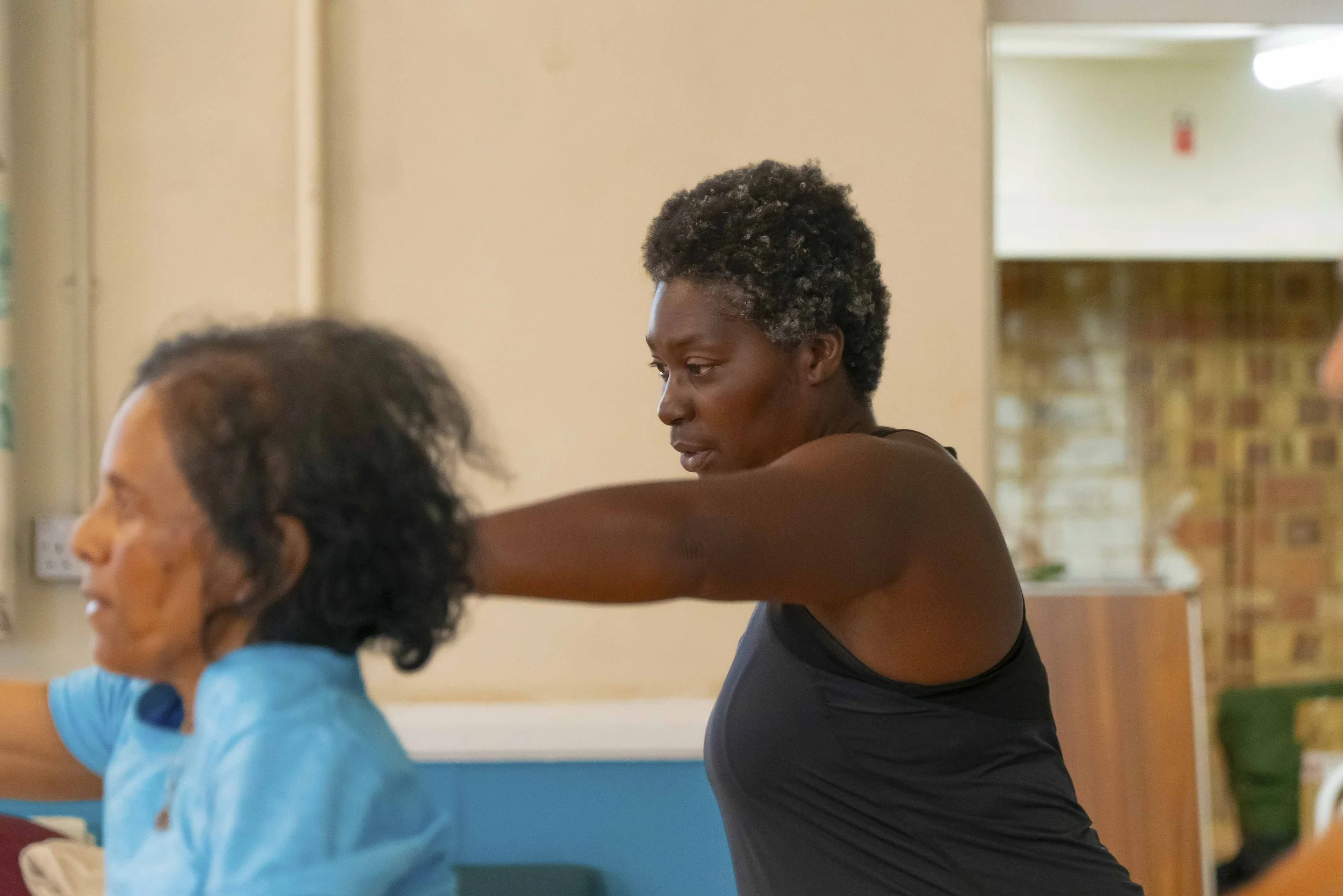 Local resident Esther with her arm stretched out in front of her, taking part in an exercise class alongside another participant