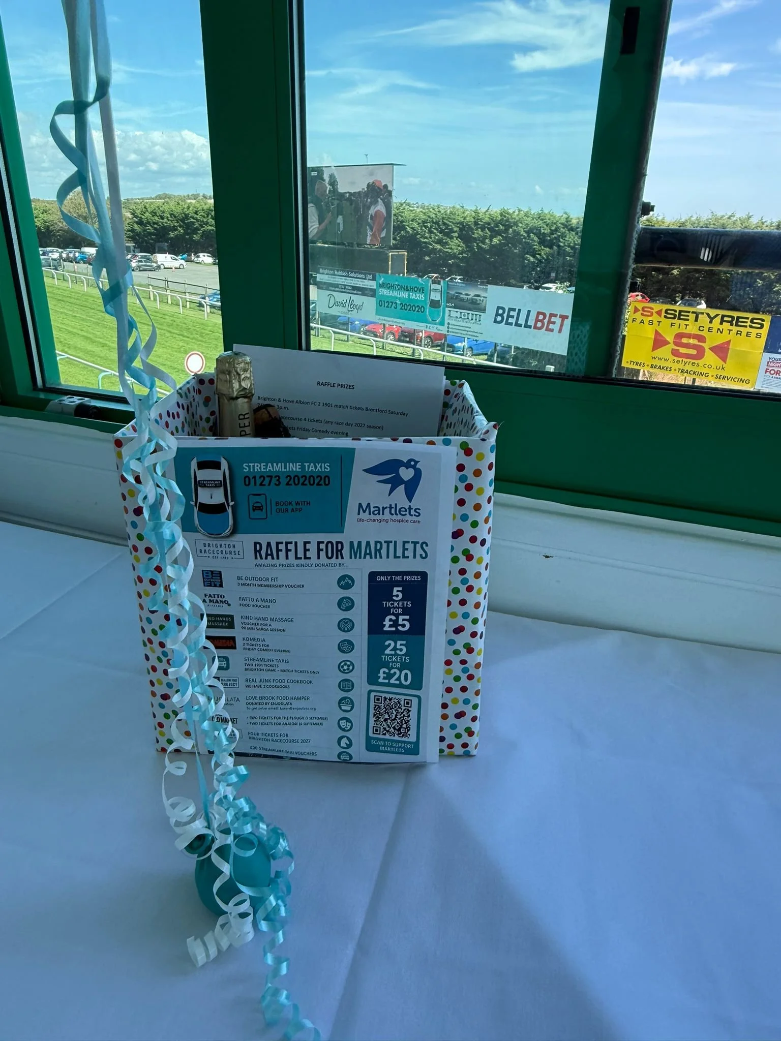 Raffle box with prizes and the official Raffle for Martlets poster at Streamline Taxis' Brighton Racecourse evening