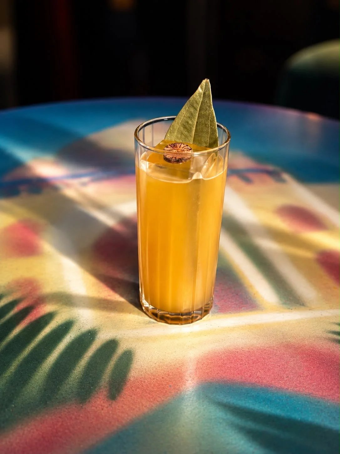 Himalayan Rum Punch at Indian Summer, a tall glass of orange cocktail garnished with a bay leaf and nutmeg