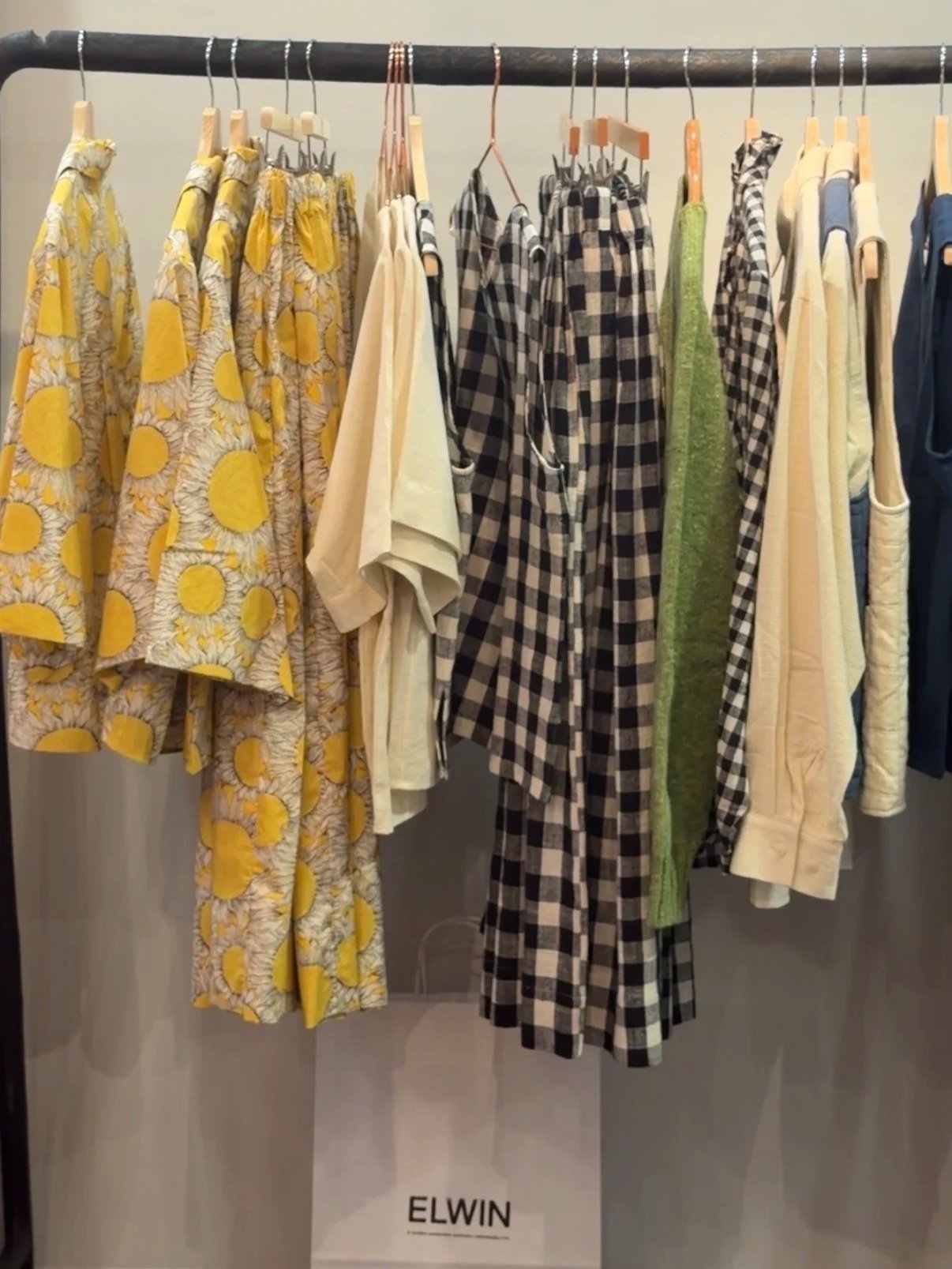 A full rail of ELWIN clothing with sunflower prints and gingham at the pop-up