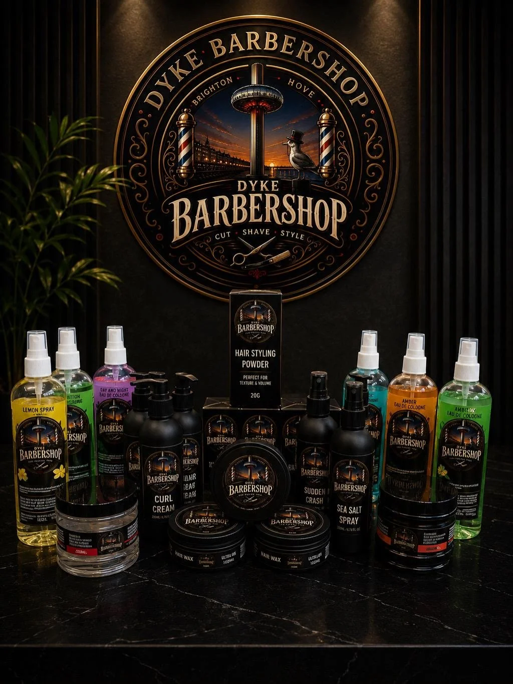 The Dyke Barbershop own-brand grooming range including styling powder, curl cream, hair wax, sea salt spray and colognes beneath the shop logo