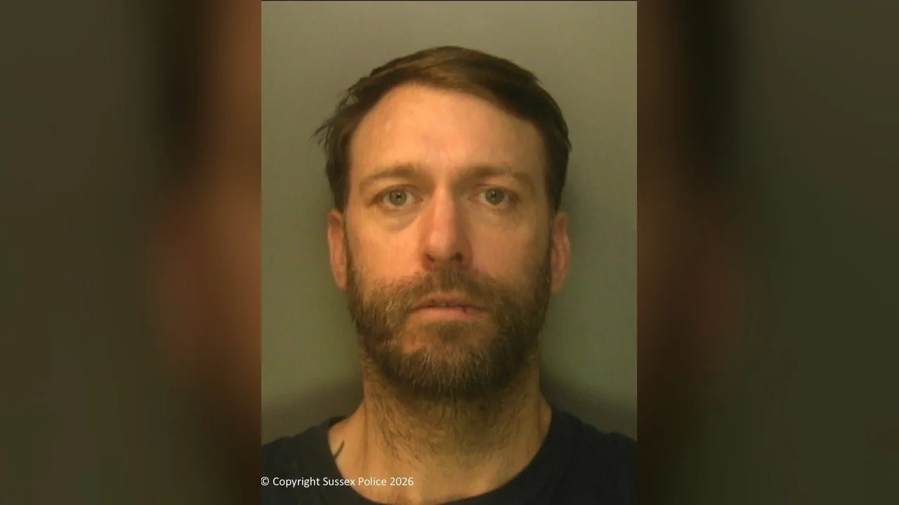 Police custody photograph of James Sinden, a man with short brown hair and a beard, against a grey green background