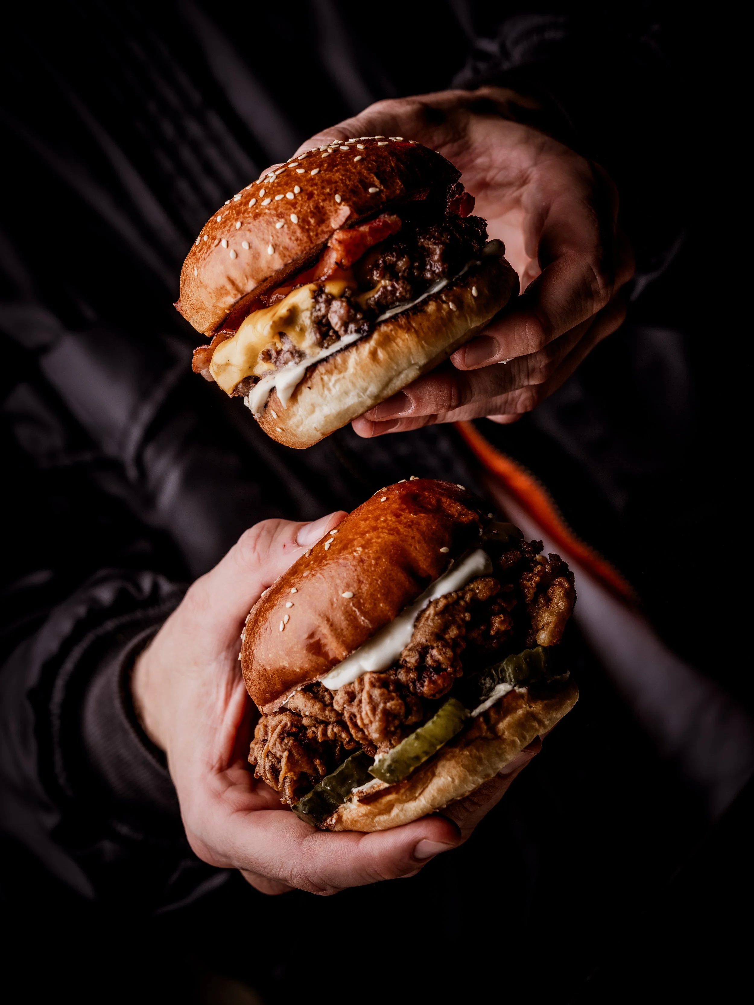 Signature Burger & Beyond burger with melted American cheese and bacon being held by a member of staff at the Brighton restaurant