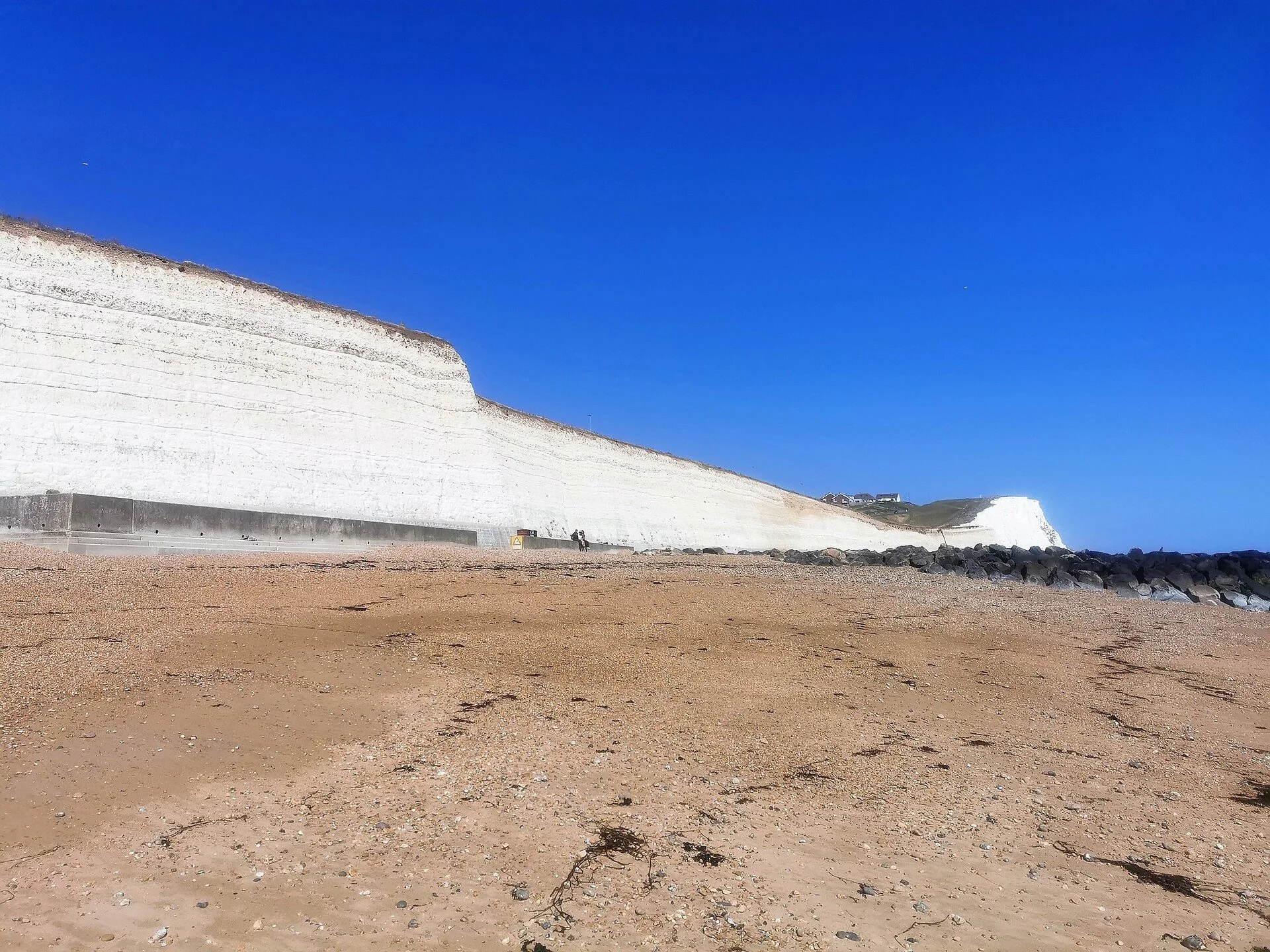 White chalk cliffs rising above the beach at Saltdean under a clear blue sky