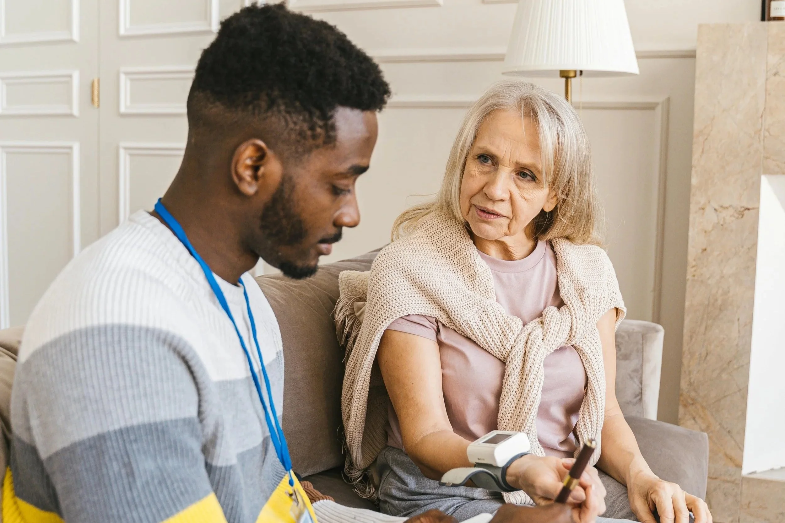 A carer carrying out a health check with an elderly woman at home