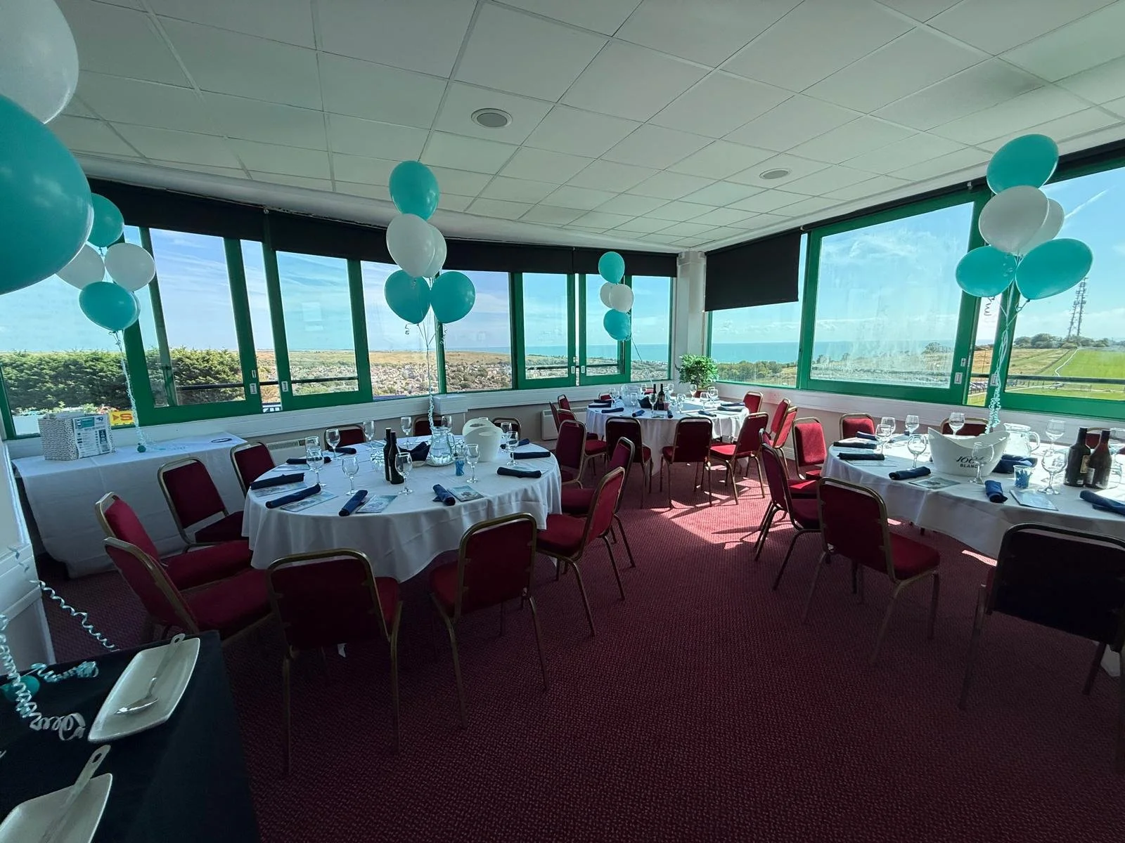 Wide view of the function room with balloons and tables set overlooking Brighton Racecourse and the sea