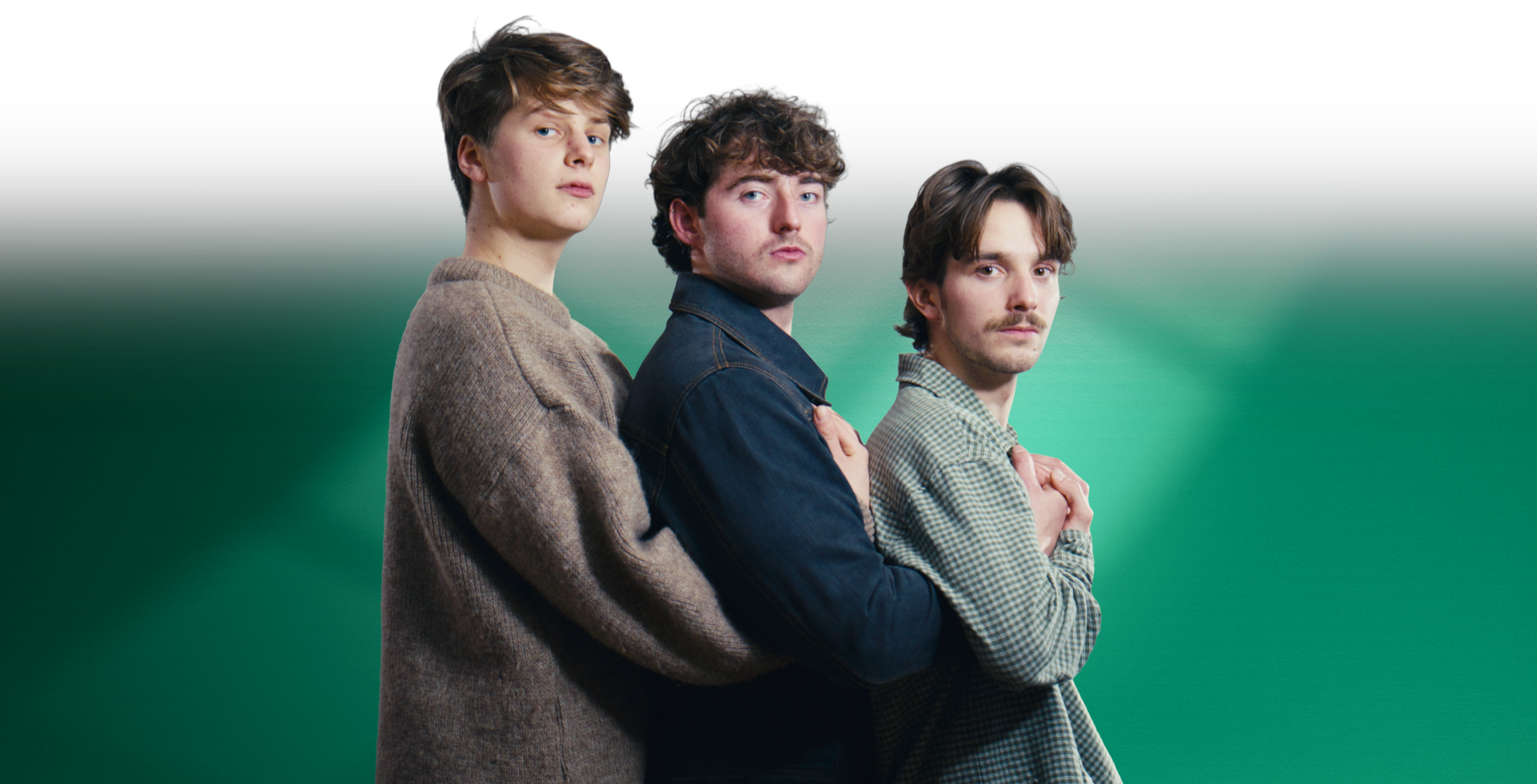 Three young men stand comedically close together, looking at the camera, with a gradient green background. These men are the three founders of Mad Heron - Joe Shale, Jasper Pagan and Lewis Kerr.