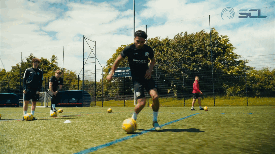 Young soccer players practicing dribbling on a field during daytime.