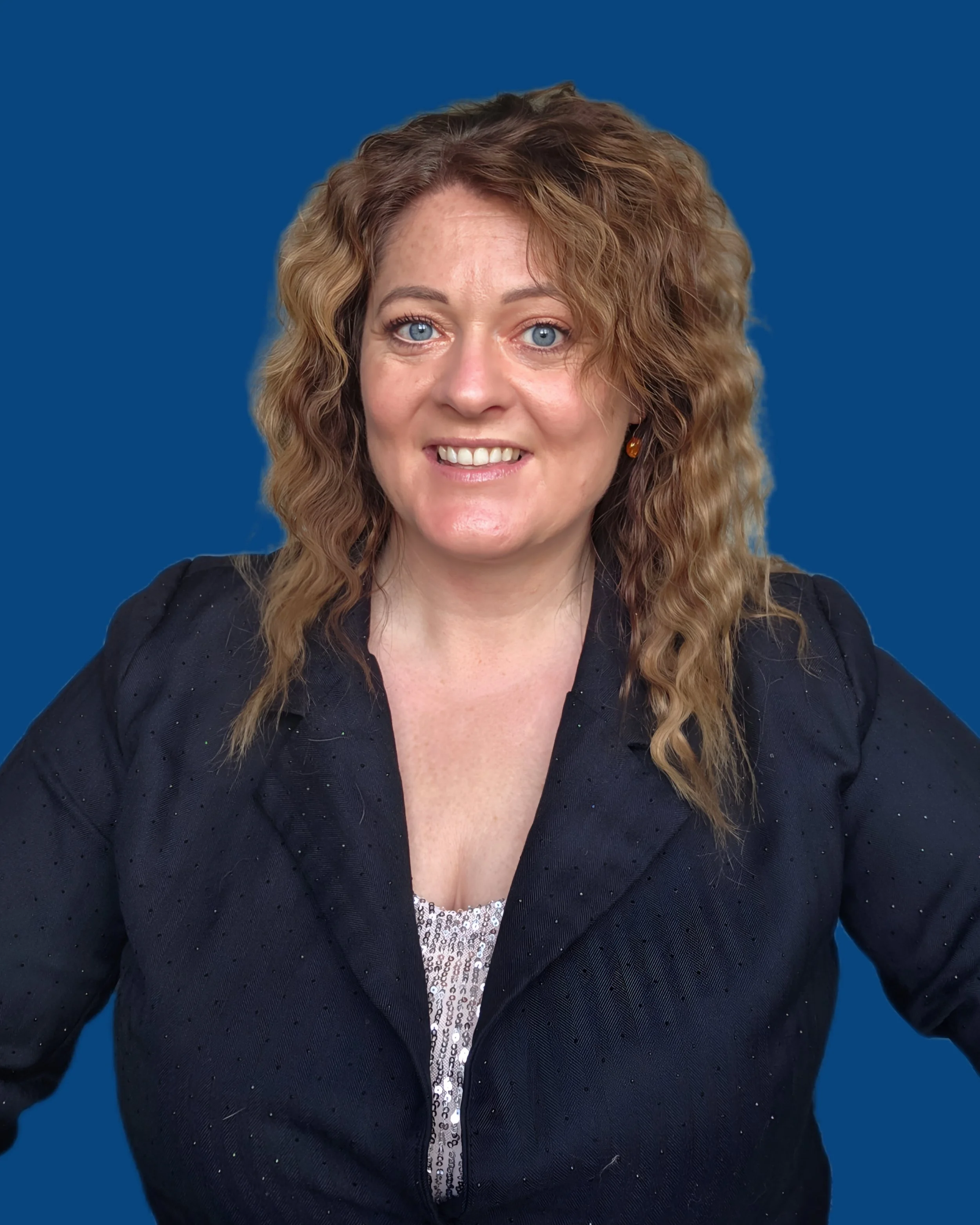 Helen Wison in a blue velvet dress standing indoors next to a pink shiny backdrop.