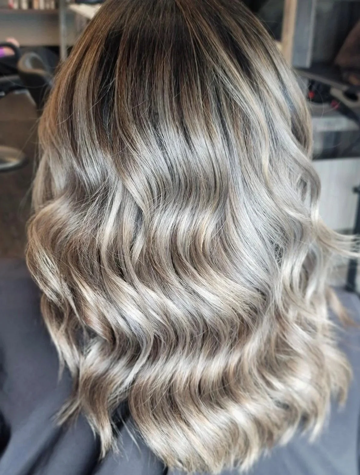 Back of a person's head with wavy, blonde hair with darker roots.