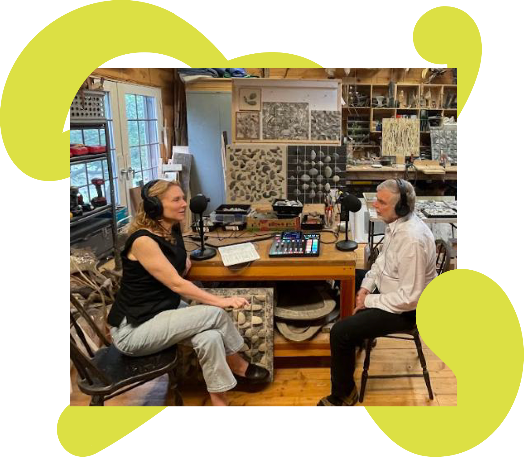 Two people with headphones and microphones recording a podcast in a woodwork workshop, surrounded by tools and wood samples.