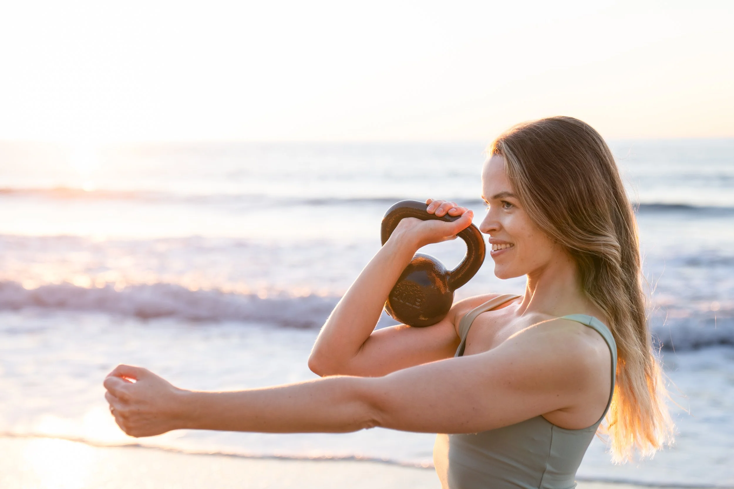 Female lifting kettlebell at the beach