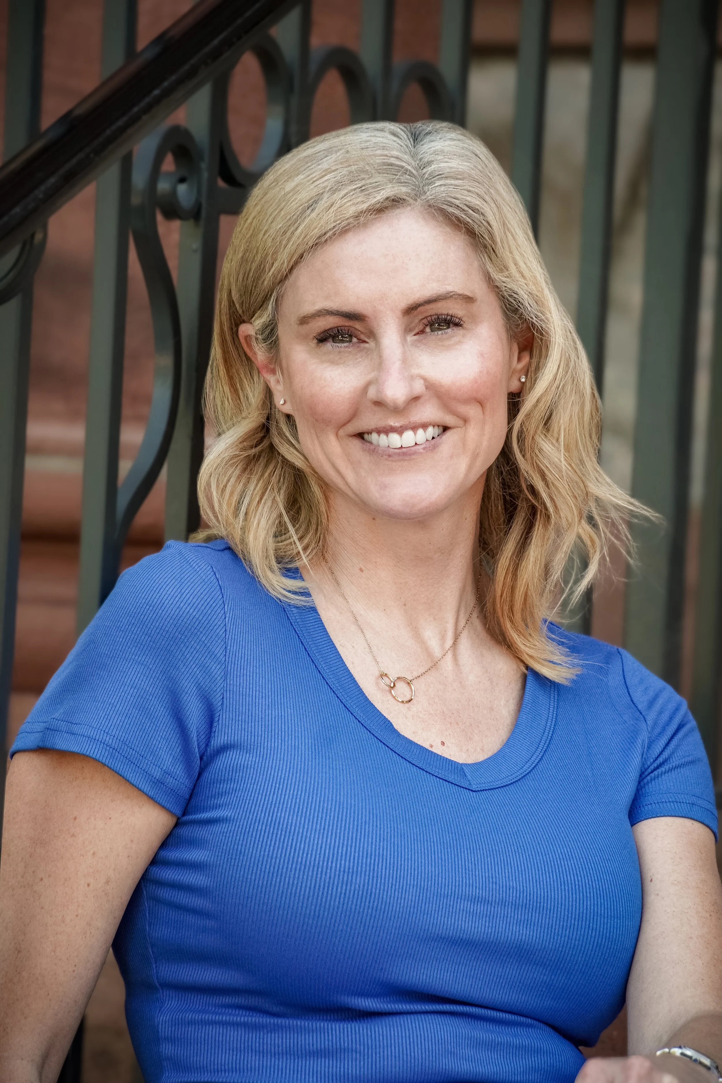 Woman in a blue shirt sitting against railing