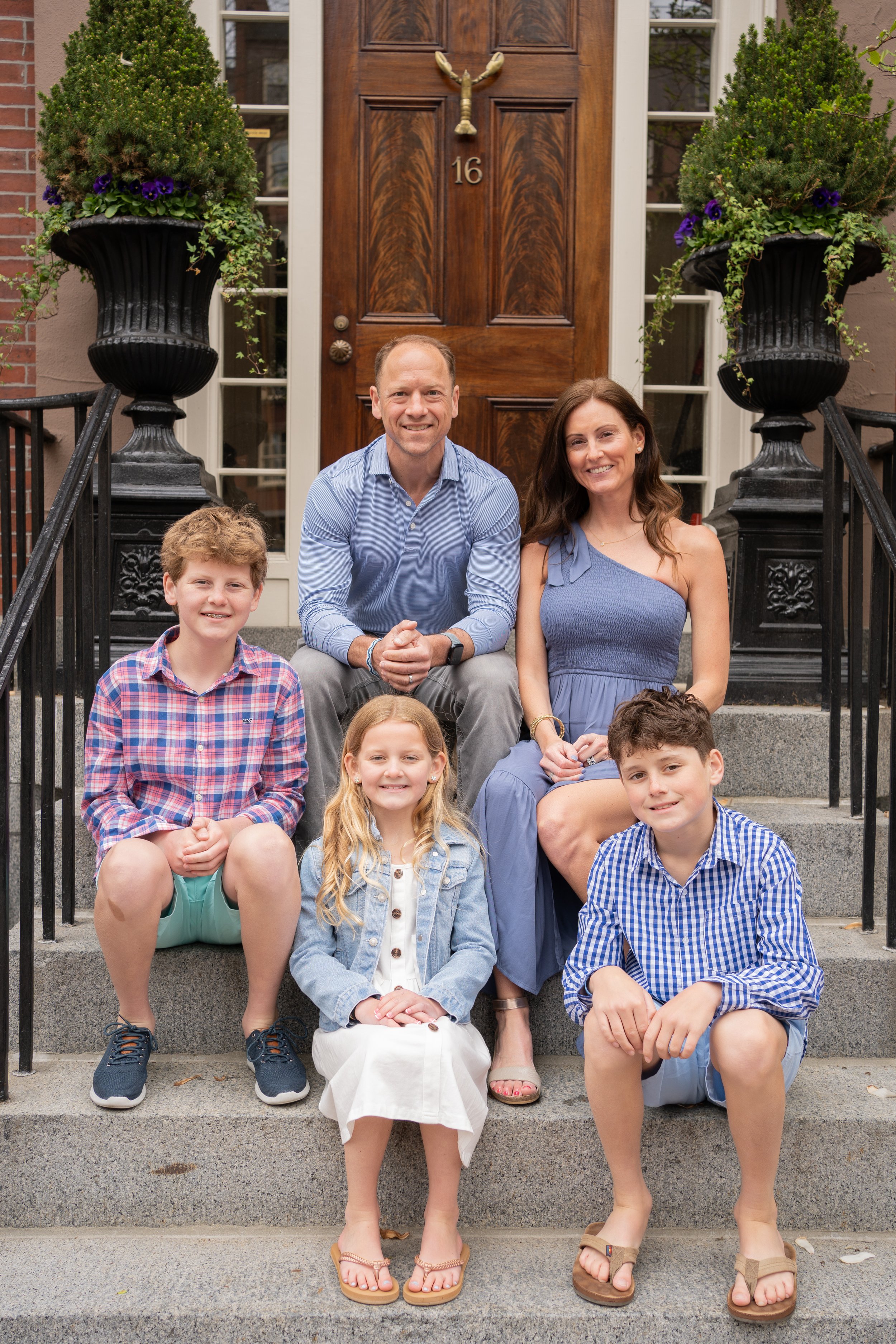 A picture of a family of five sitting on the stairs