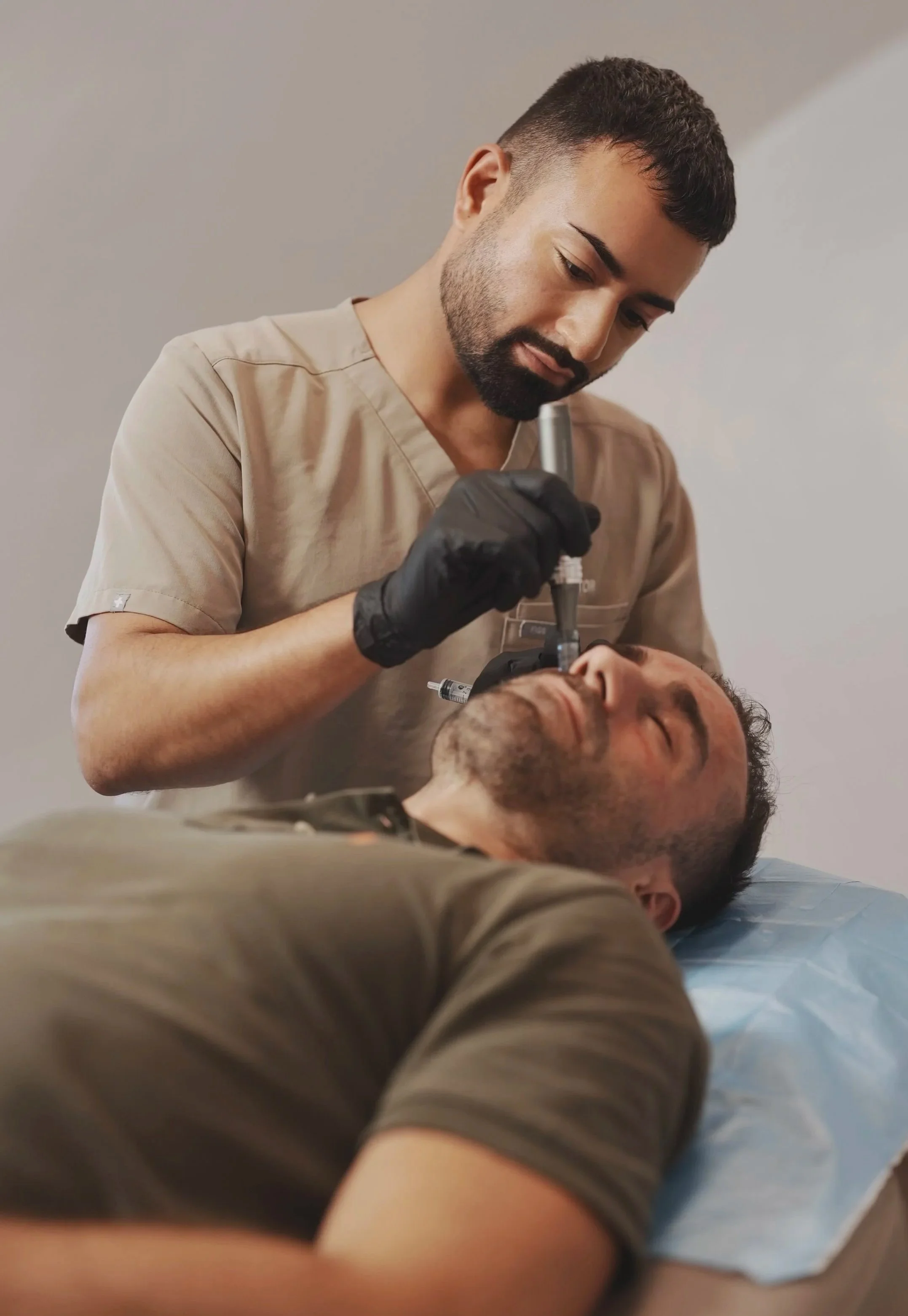 A medical professional performing a procedure on a patient lying down, using a medical instrument for a nose or facial treatment.