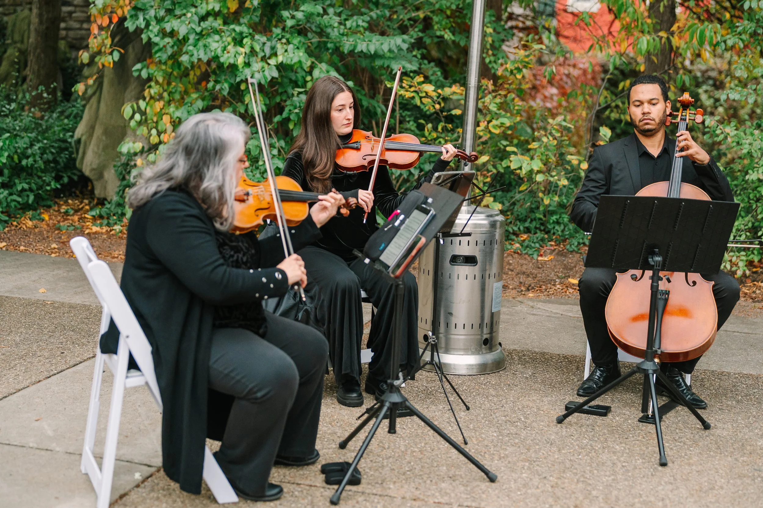 Radiant Strings trio (two violins and cello) playing outdoors.