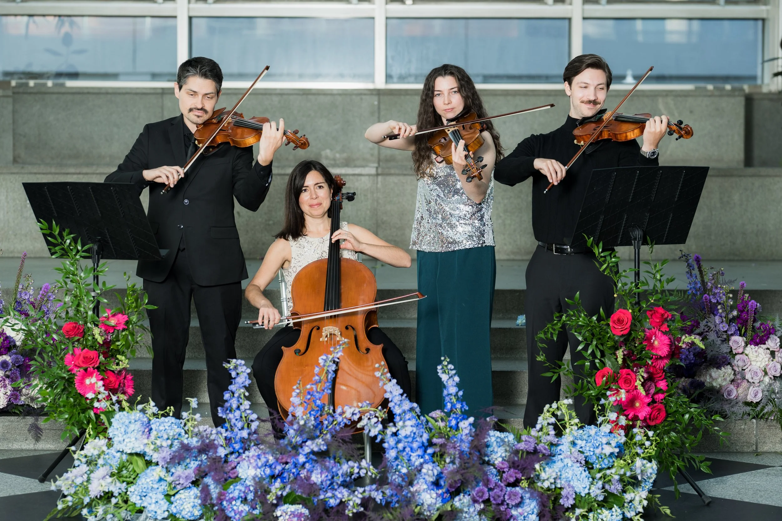 Erin Higgins performing with Radiant Strings on a stage decorated with flowers.