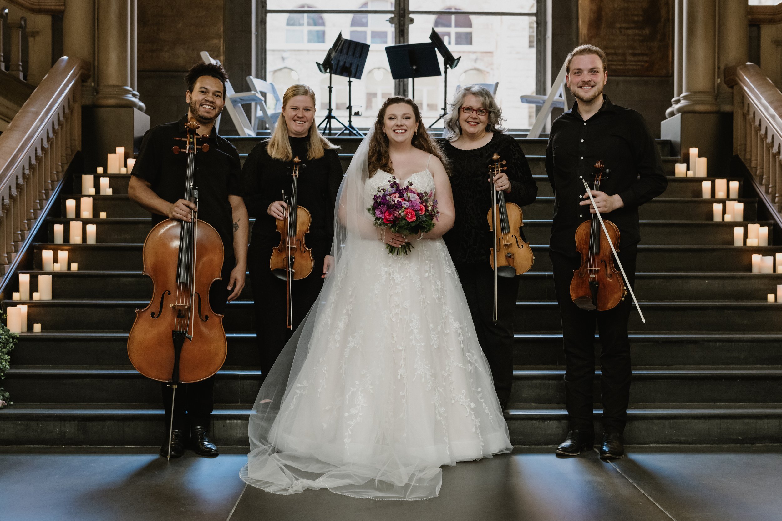 Nicole in her wedding gown holding a bouquet of flowers standing with Radiant Strings in the Allegheny County Courthouse.