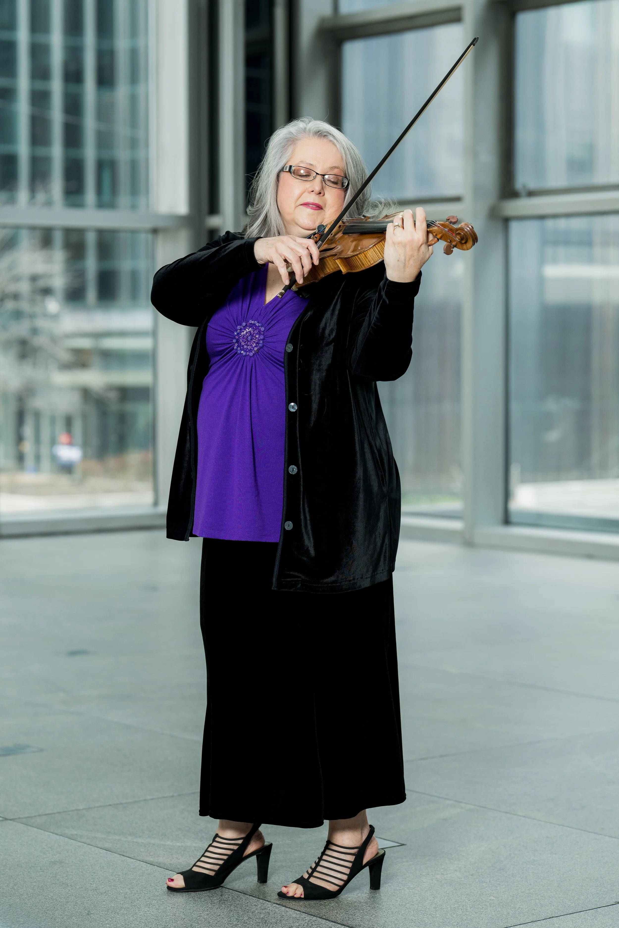 Jennifer Madge playing the violin indoors near large windows.