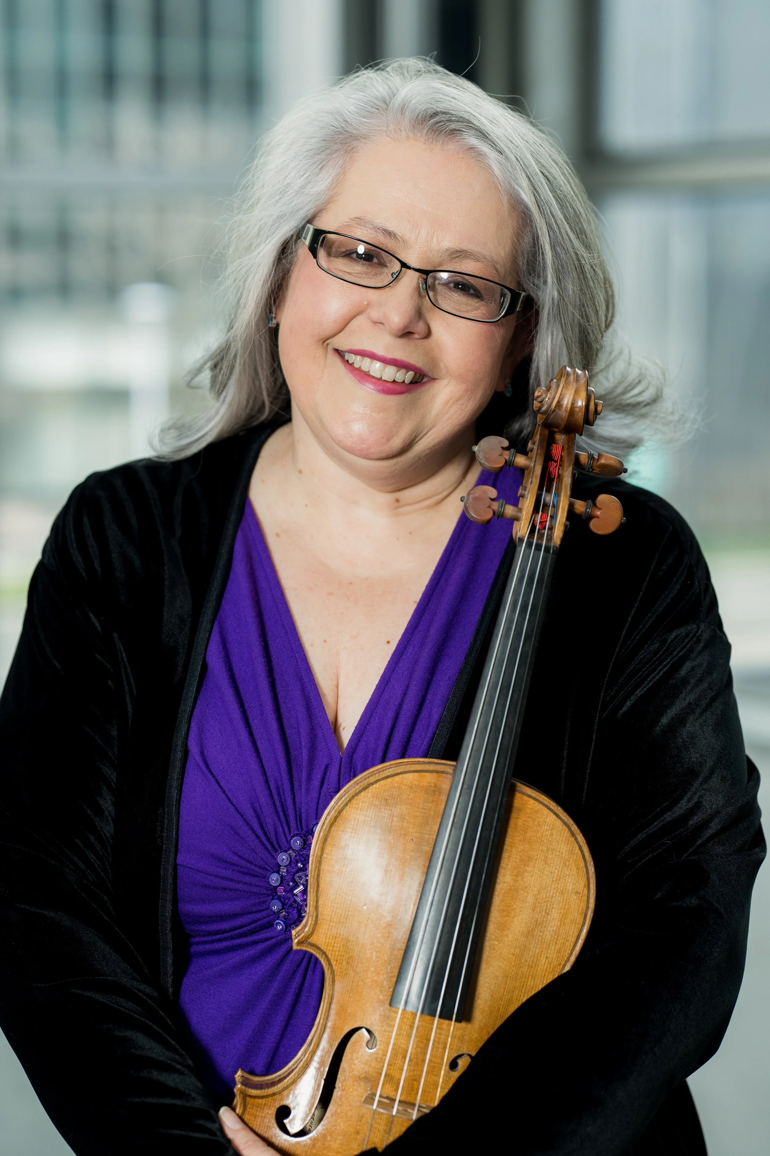 Jennifer Madge smiling and holding her violin.