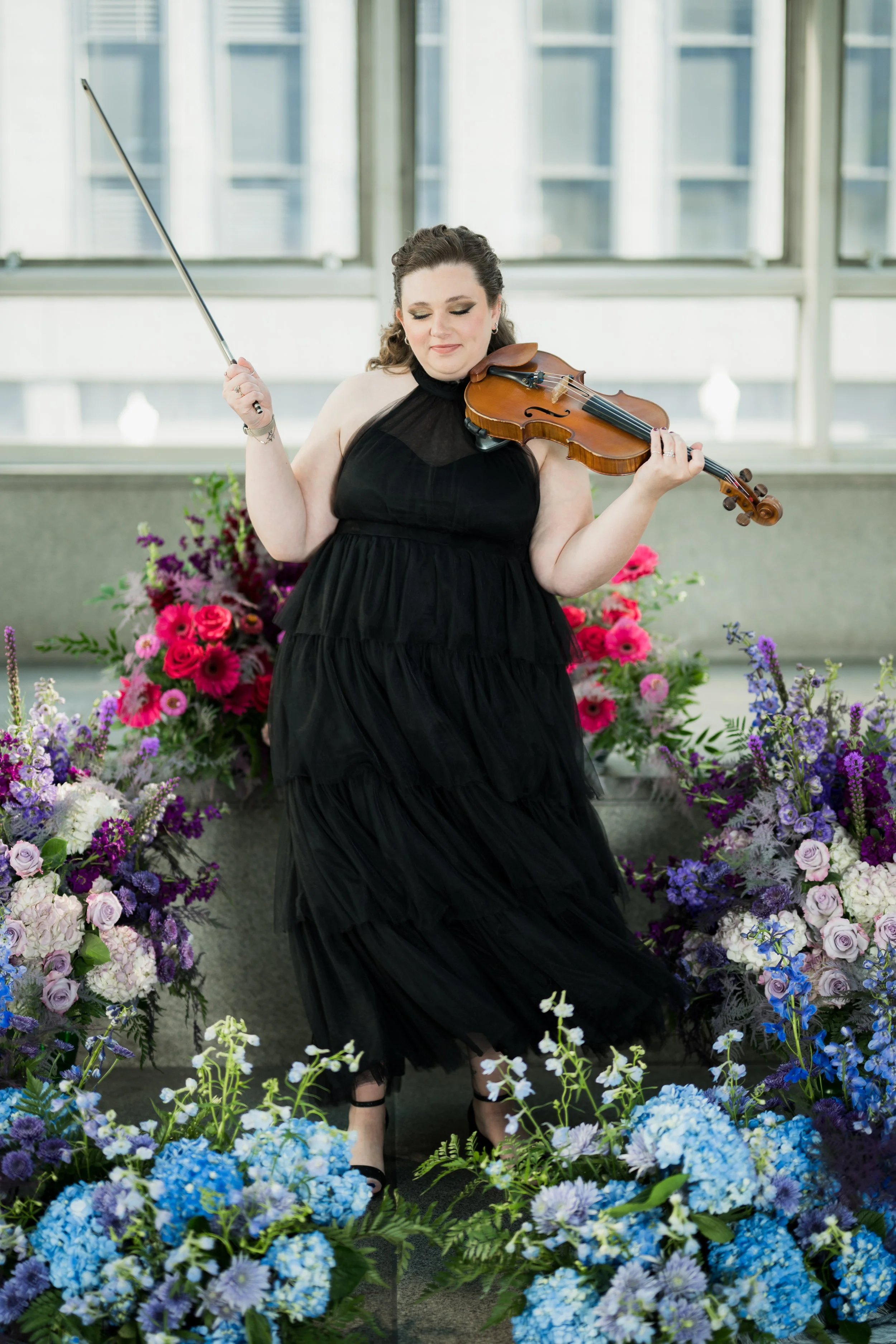 Nicole Lennartz twirling her dress while flourishing her violin bow.