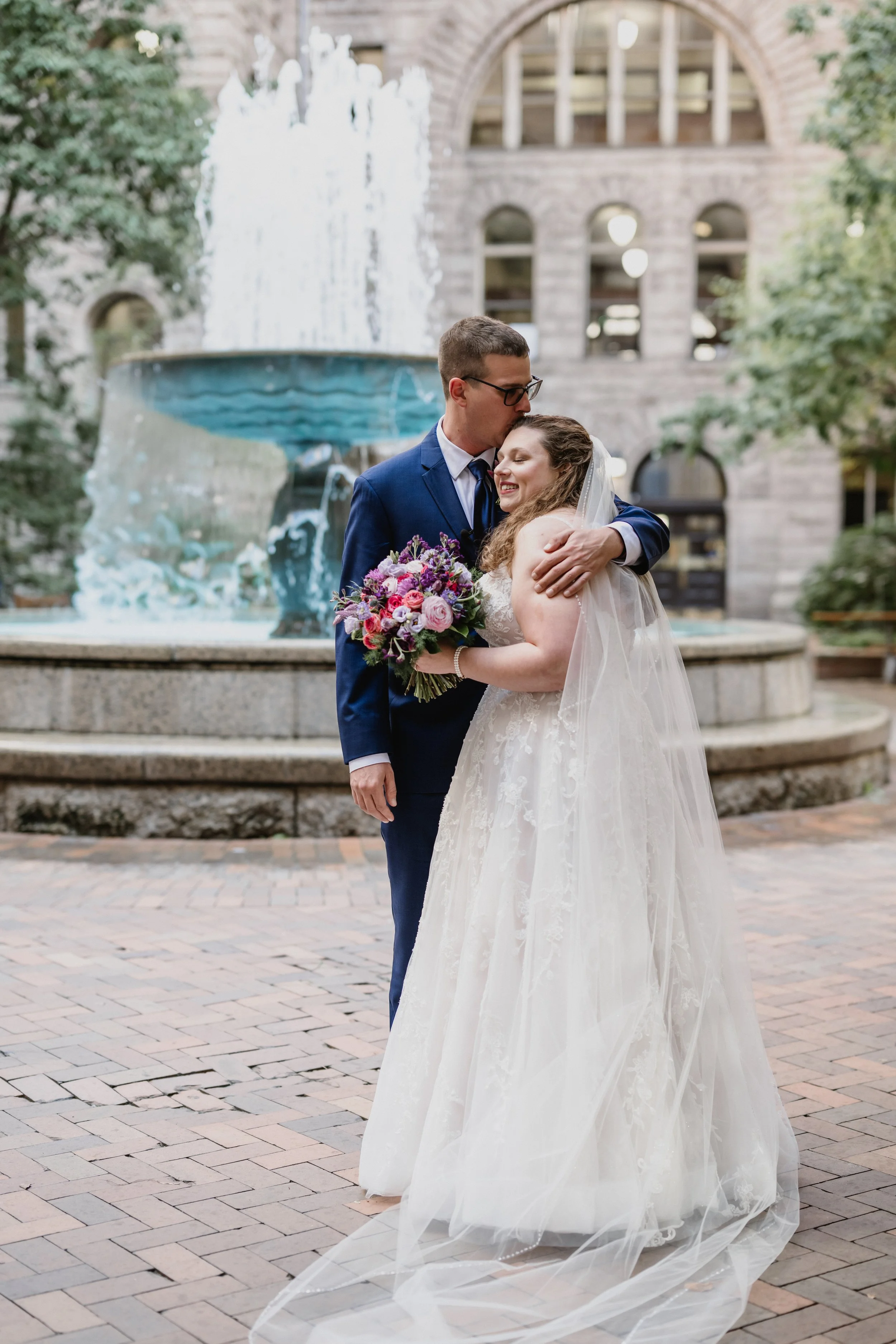 Nicole and Devin sharing a tender moment in front of a fountain at the Allegheny County Courthouse.