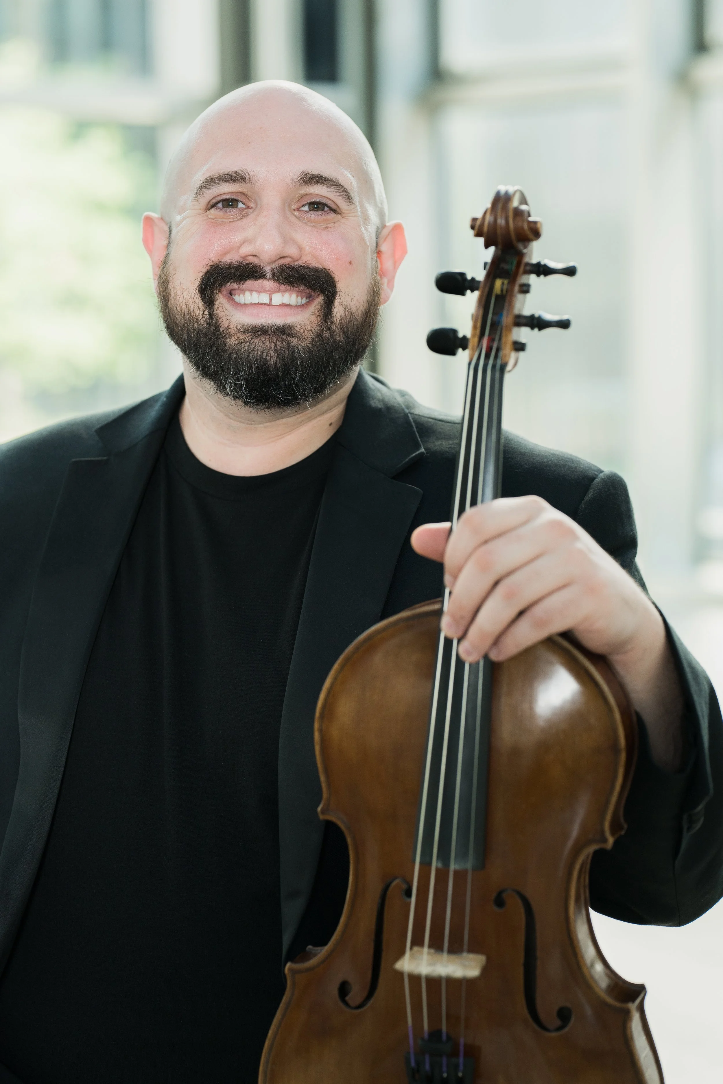 Stephen Weiss smiles and holds his violin.