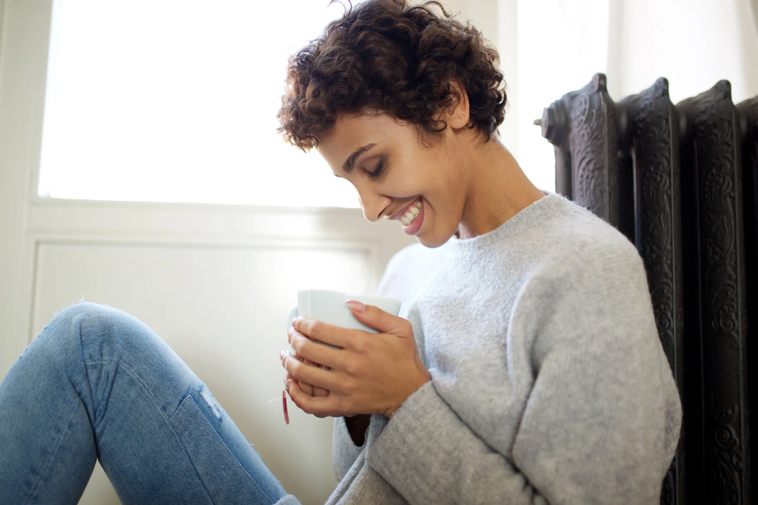 Lady leaning on radiator warmed by the air source heat pump