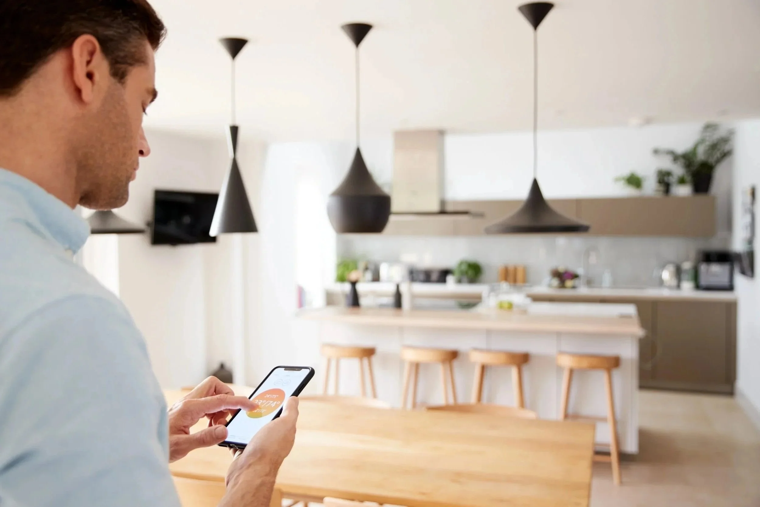 Man adjusts the thermostat in his kitchen after new boiler installation in kingston surrey