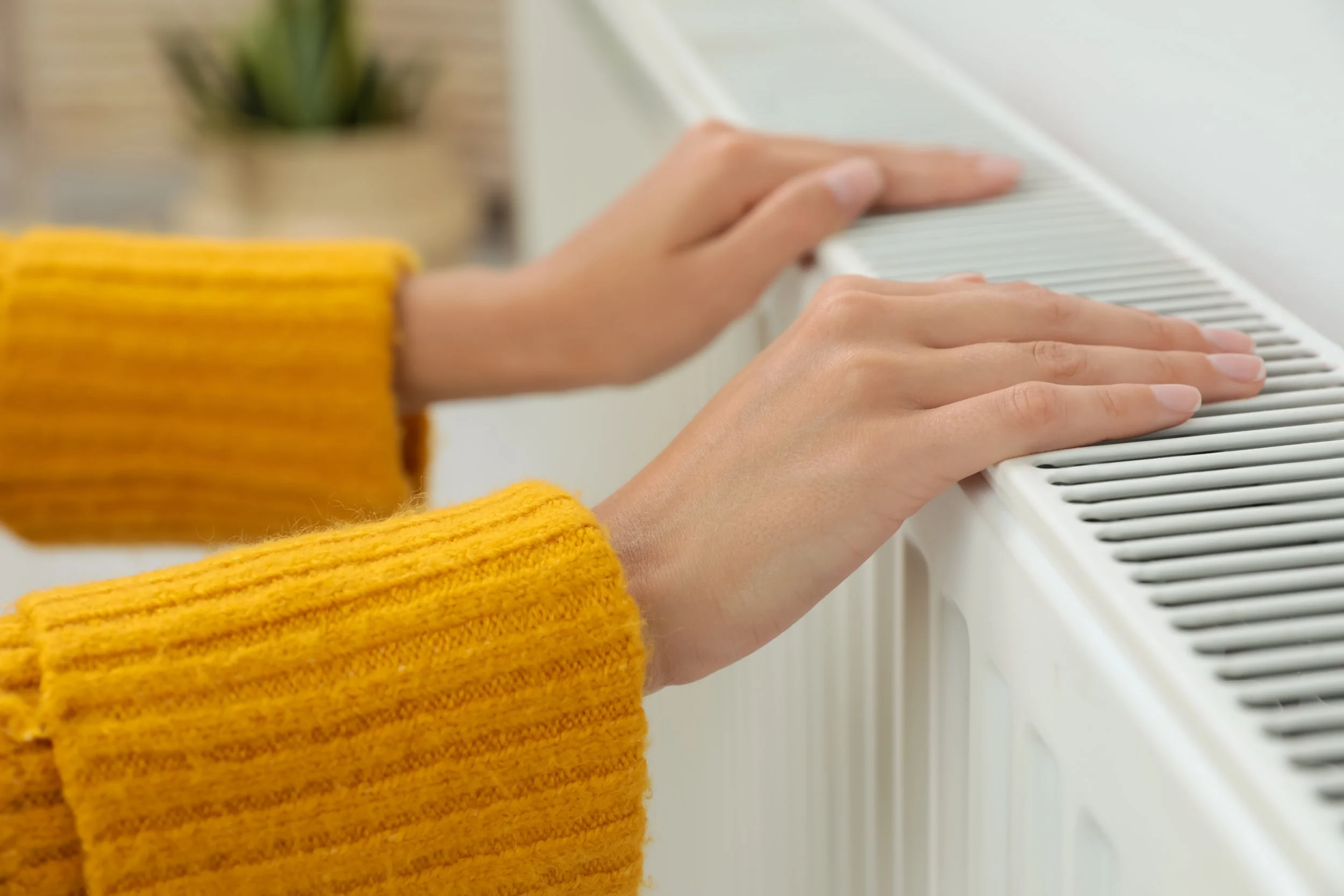 Lady putting her hands on the warm radiators after the heating syste powerflushing by expert plumbers in Wimbledon SW19