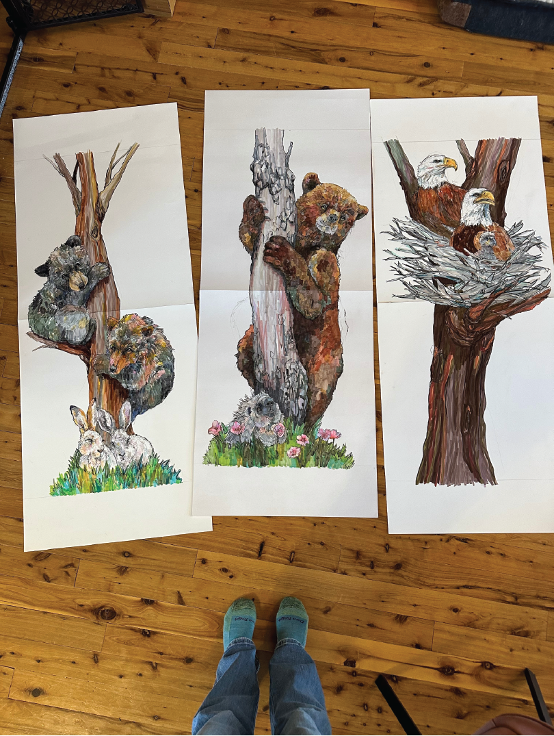 The left poster shows two bears in a tree with two rabbits at the base, the middle poster depicts a bear cub clinging to a tree trunk with a small porcupine below, and the right poster features two bald eagles sitting in a nest on a tree branch.