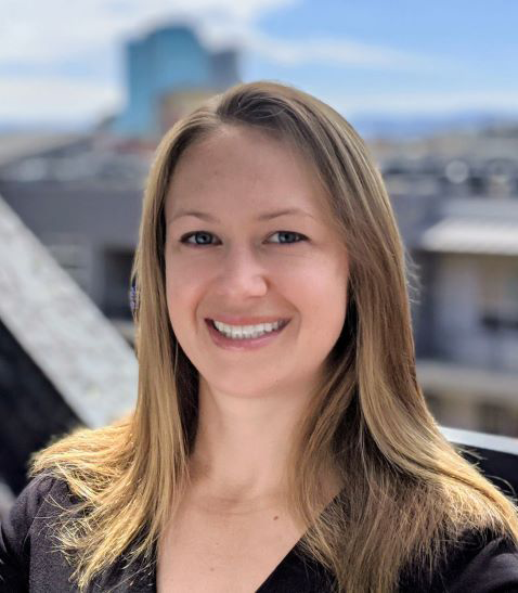 A woman with long blonde hair smiling outdoors with a cityscape in the background under a blue sky. Ellen Scott Williams Director on the board of directors