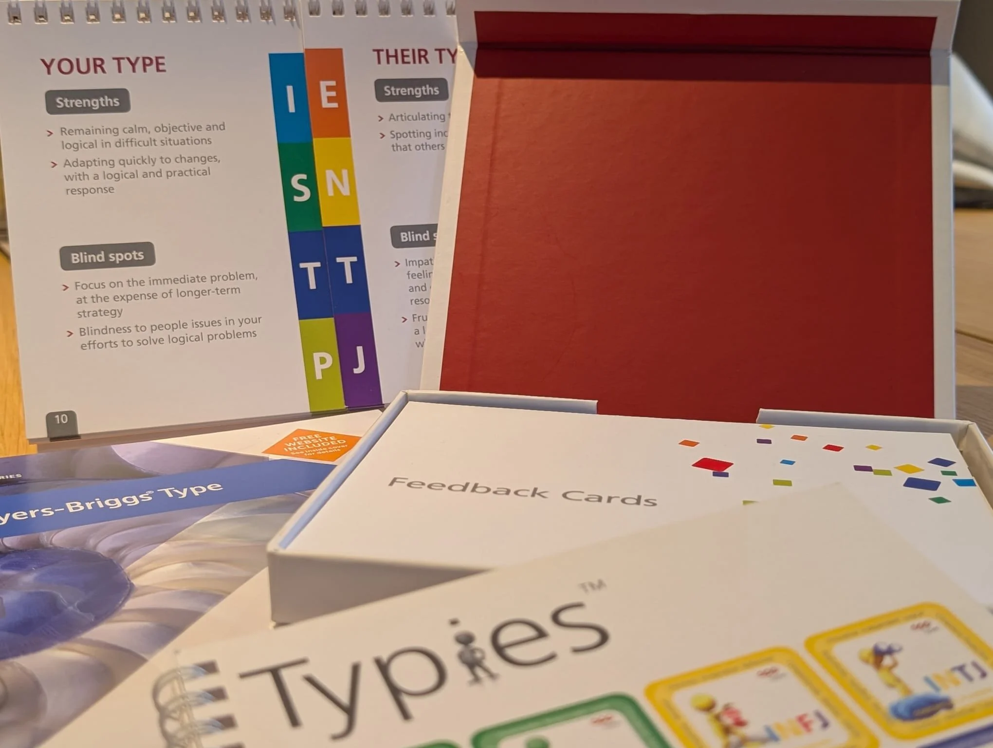 Board game boxes and feedback cards on a wooden surface, with game instructions and colorful design elements visible.