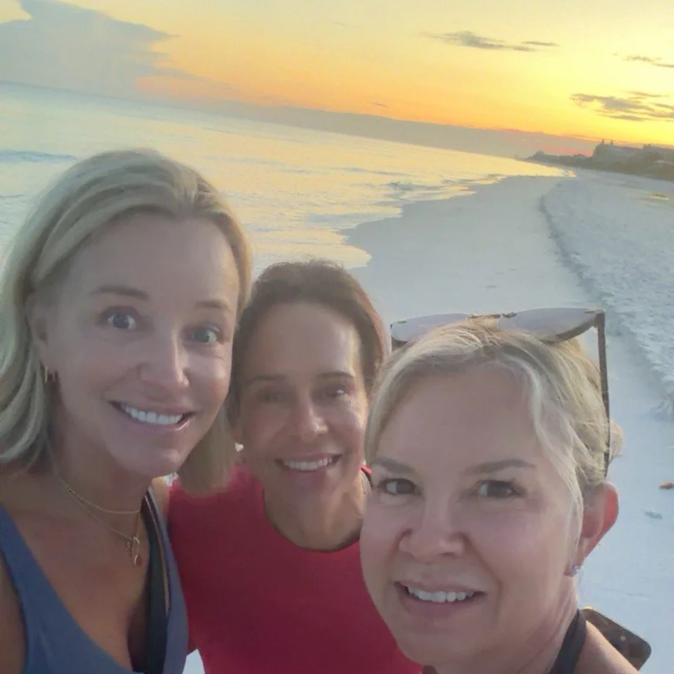 Three friends watching the sunrise on a beach walk during a girls trip