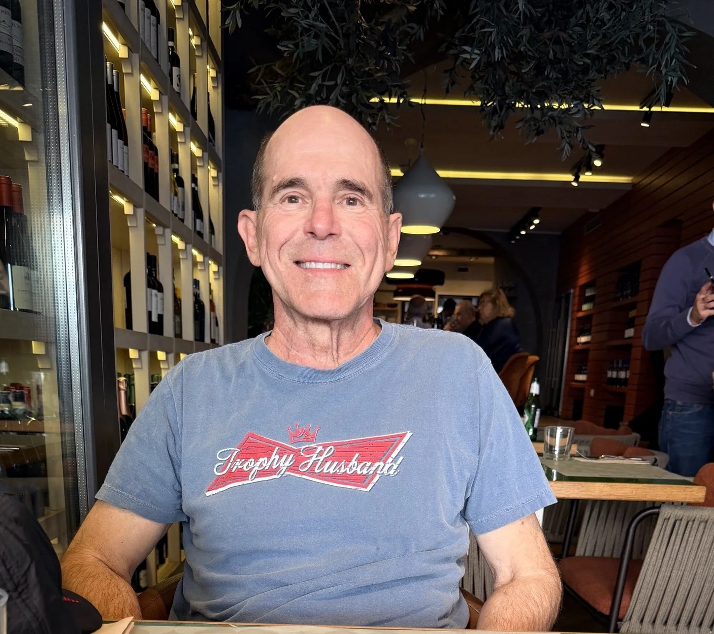 Jeff wearing a Trophy Husband t-shirt at a restaurant in Italy