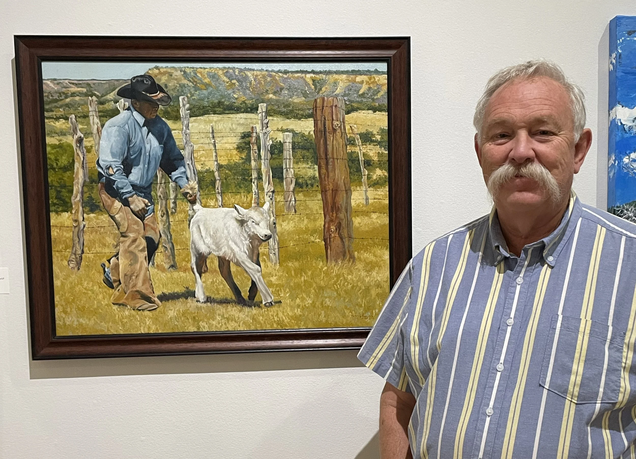 Tommy Rodgers, the artist, standing in front of one of his paintings.