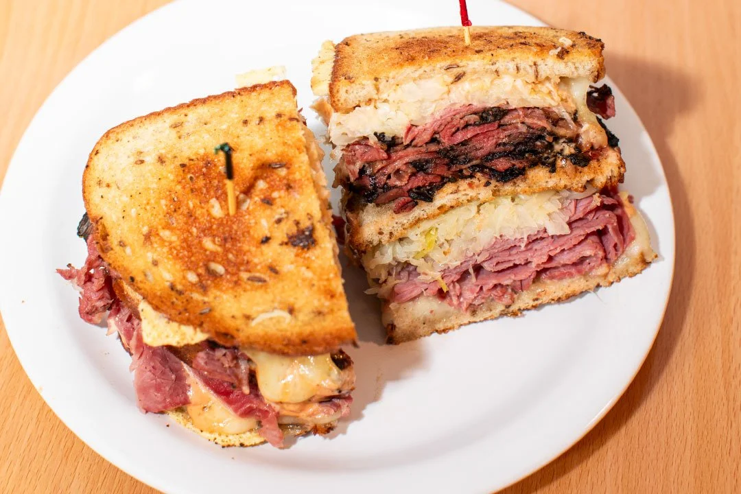 Half of a Reuben sandwich with corned beef, sauerkraut, Swiss cheese, and Russian dressing on toasted rye bread