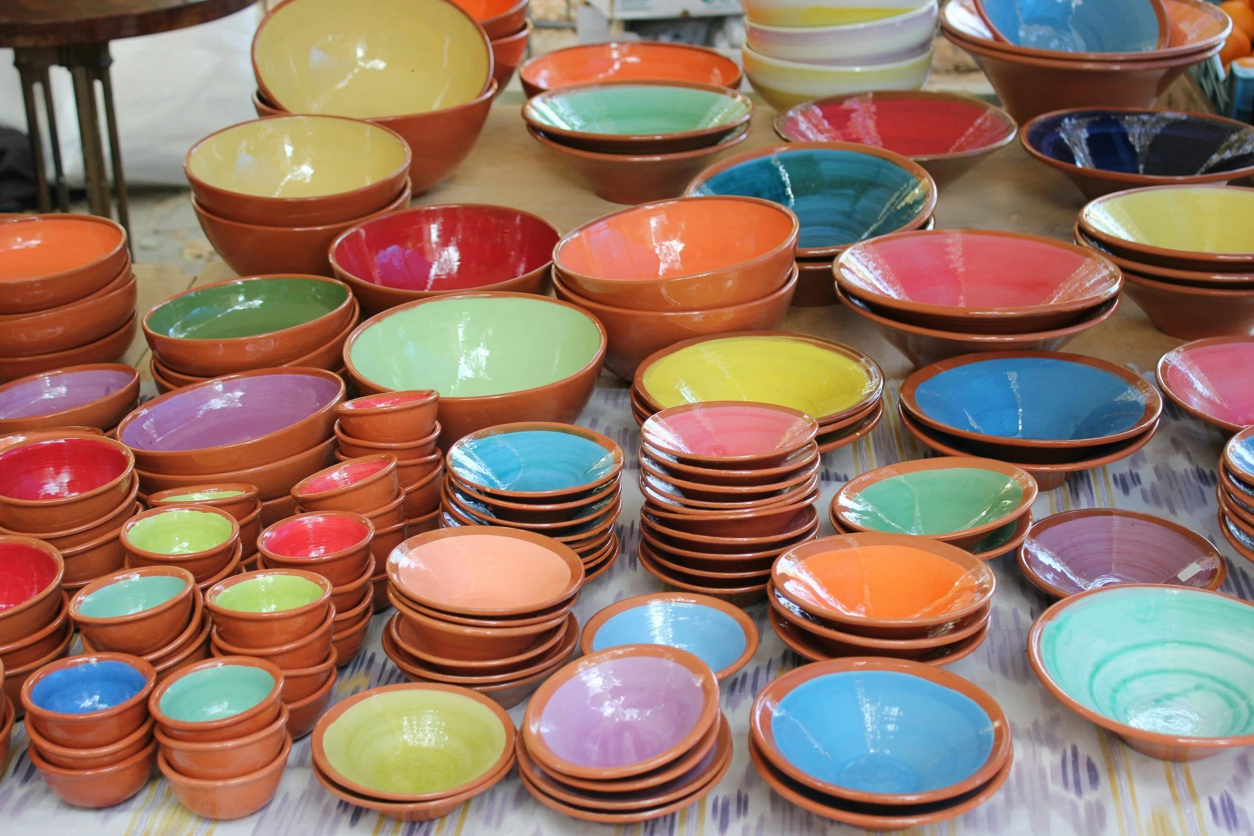 Colorful ceramic bowls in various sizes on a table, arranged in stacks and groupings.