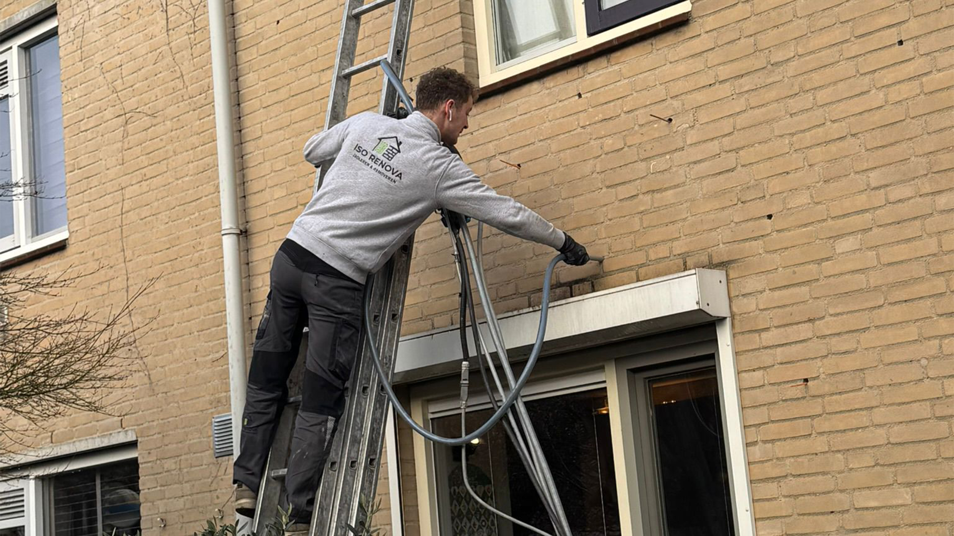 Specialist voert spouwmuurisolatie uit aan een gevel van een woning voor betere isolatie en hoger wooncomfort.