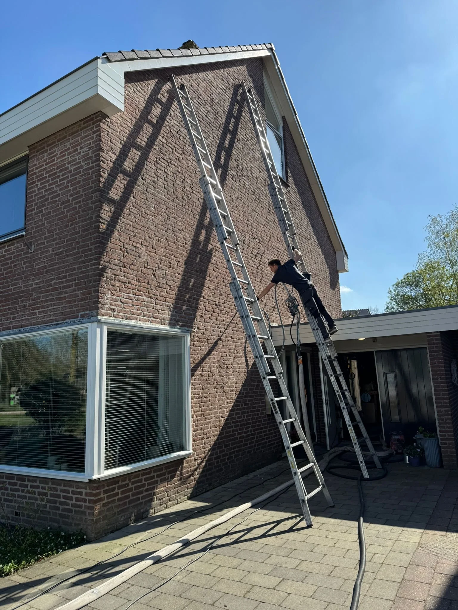 Monteur brengt spouwmuurisolatie aan bij een woning met bakstenen gevel voor betere isolatie en lagere energiekosten.