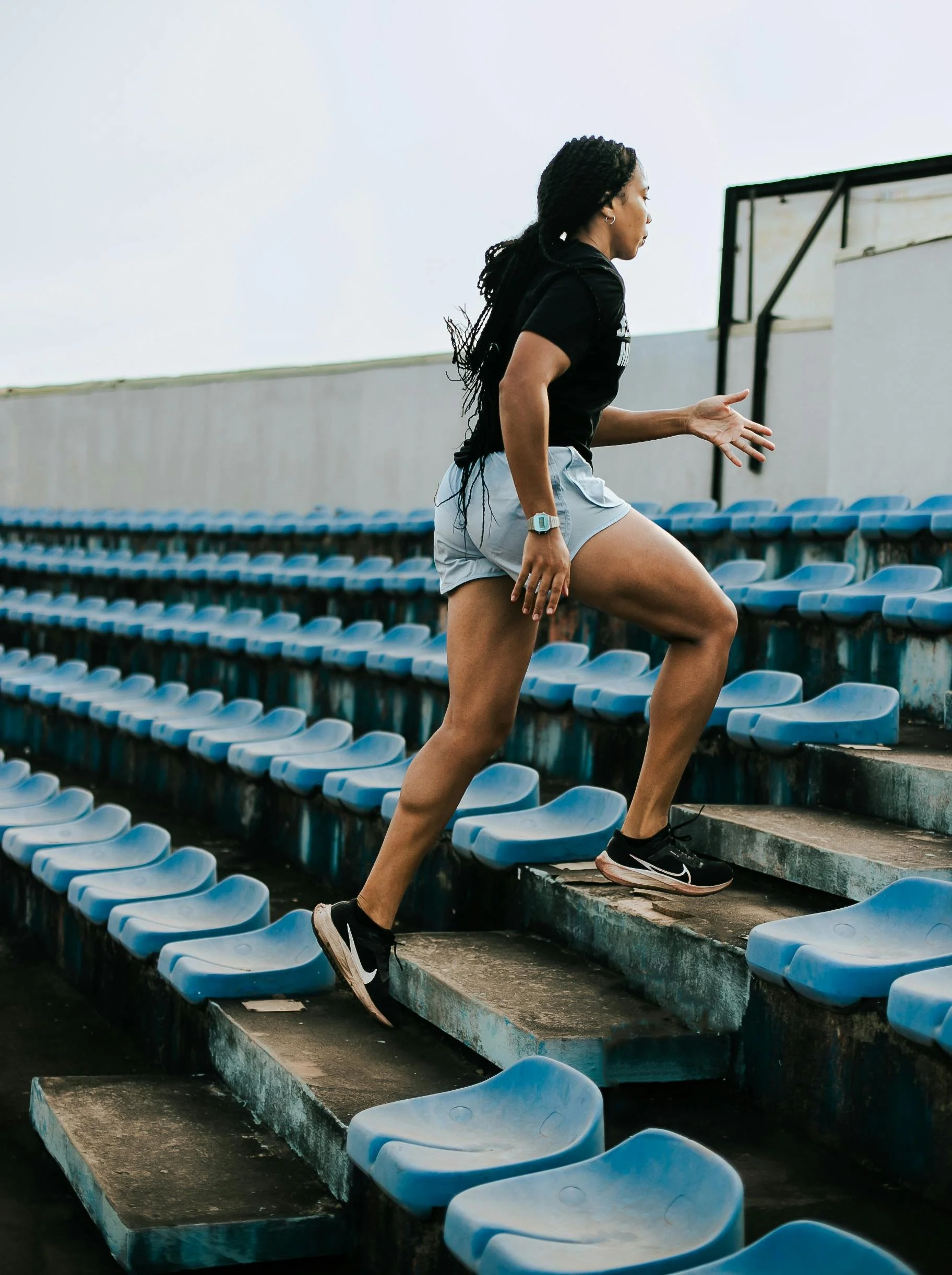 Woman running up outdoor stadium stairs with blue seating