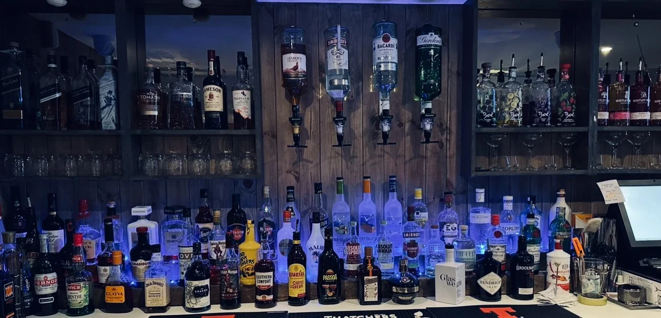 A bar with various bottles of liquor displayed on shelves and illuminated with blue LED lights.