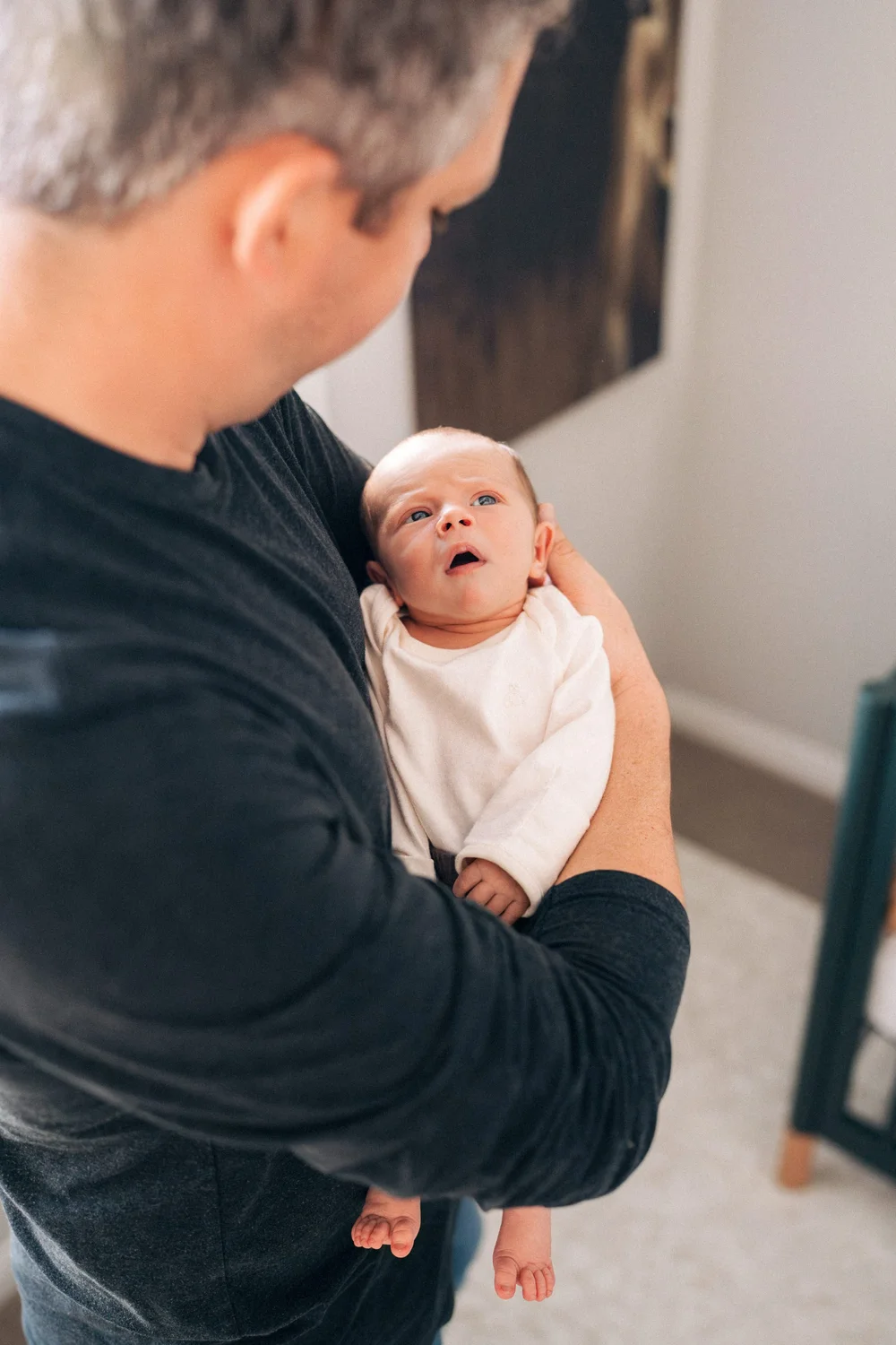 Dad holding newborn close, both looking at each other in the nursery, Hunter family in-home session Rancho Mission Viejo