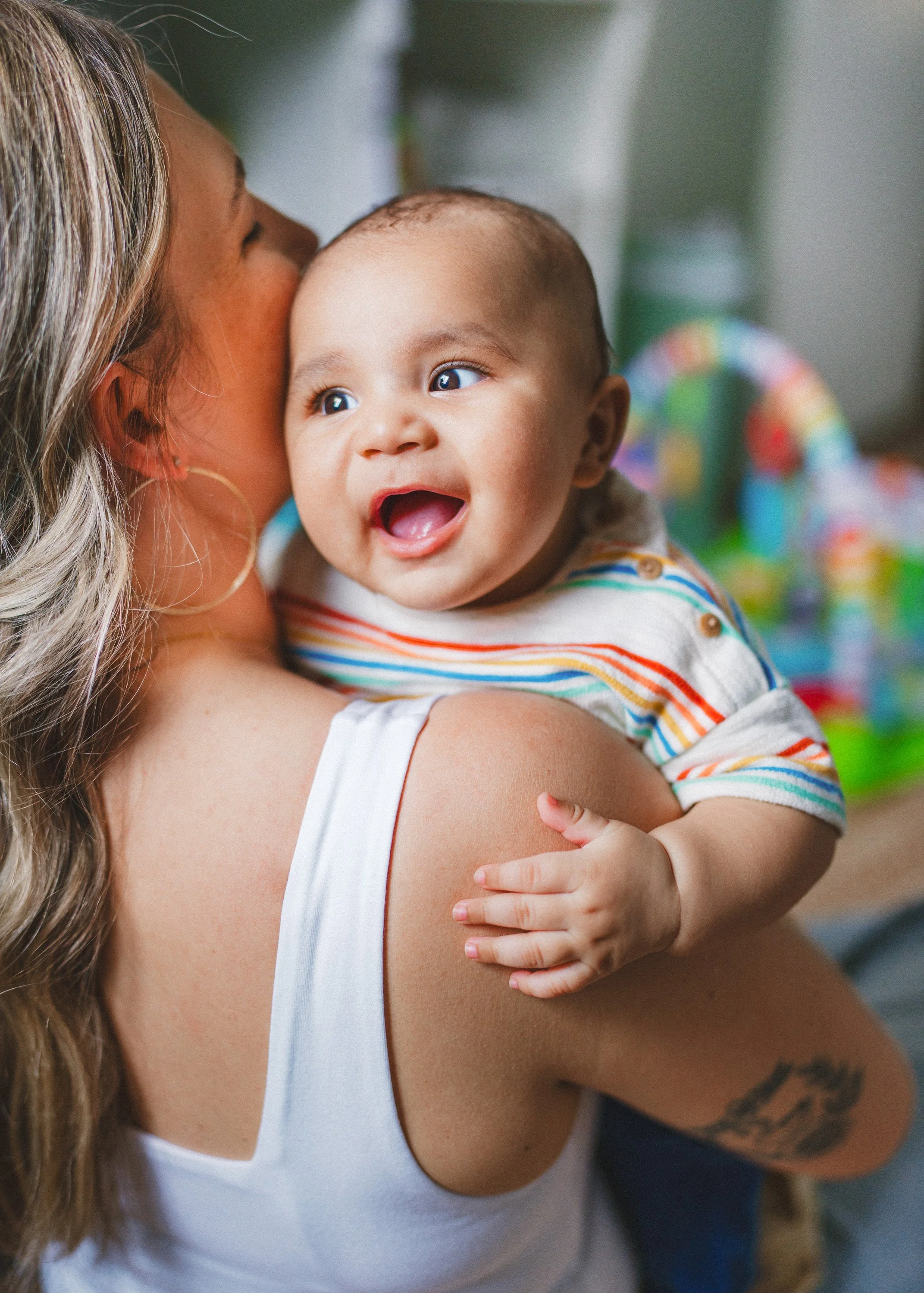 A woman holding a smiling baby with a colorful background.