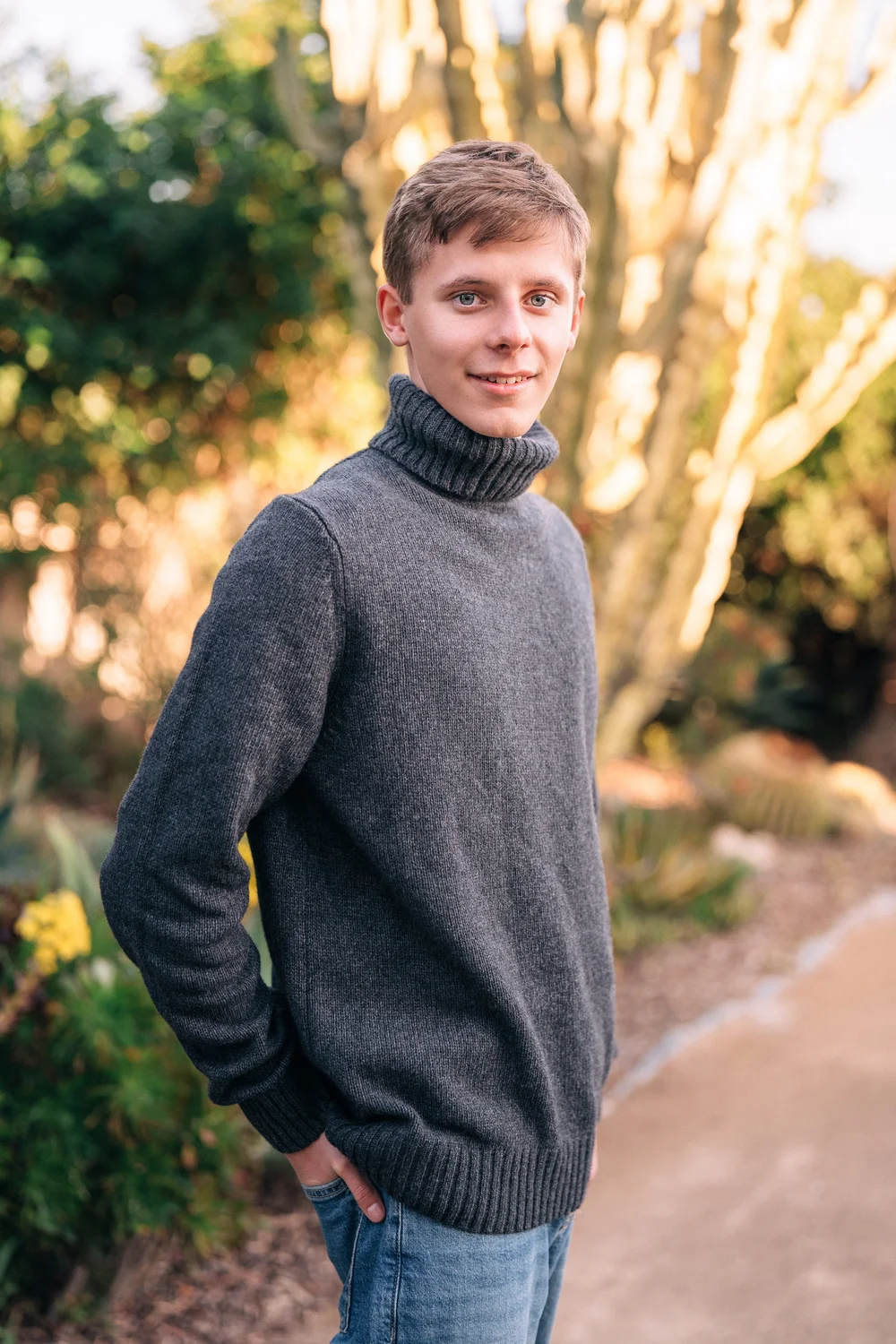 Christian in a charcoal turtleneck on a garden path at Mission San Juan Capistrano