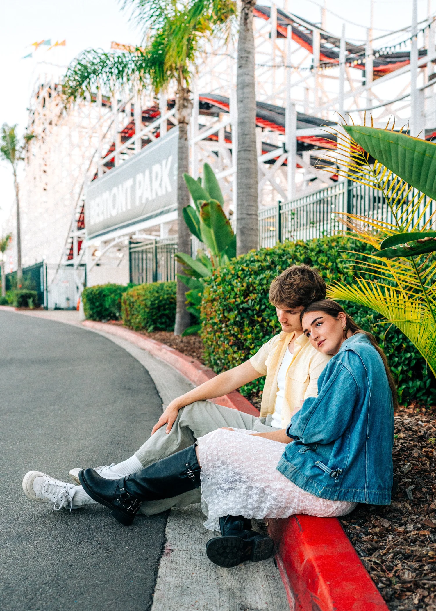 Quinn and Parker sitting on the curb beside the Belmont Park entrance, San Diego anniversary session