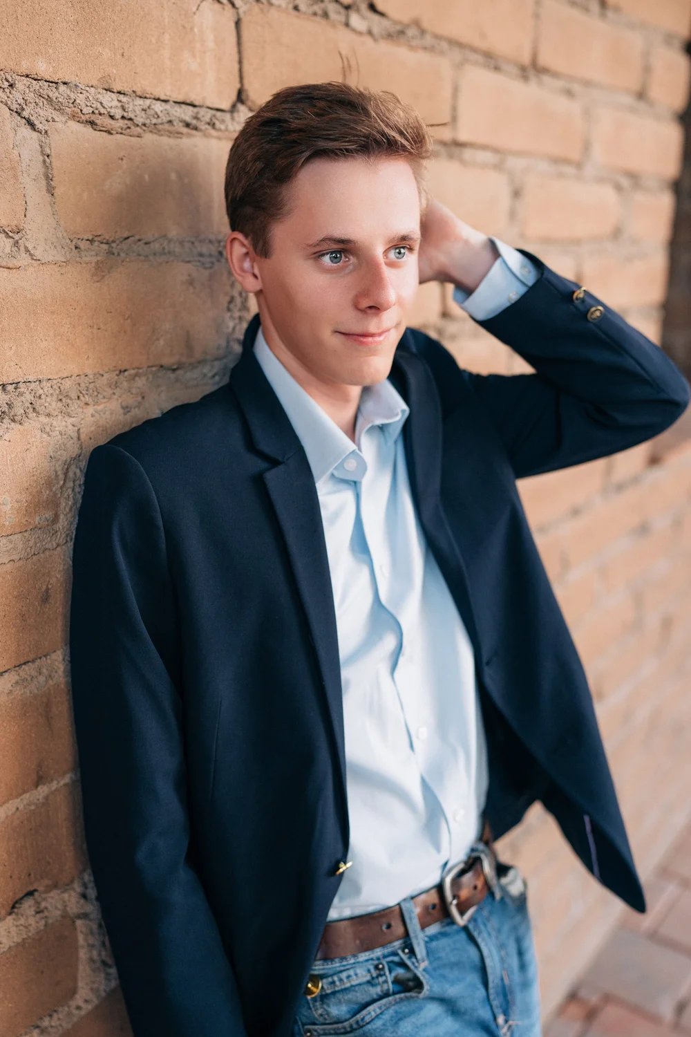 Christian in a navy blazer leaning against a brick wall, Mission San Juan Capistrano senior session