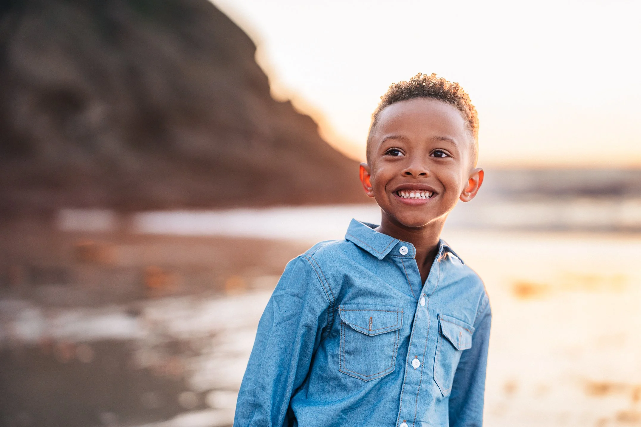 A close-up of their son grinning in the last warm light of day